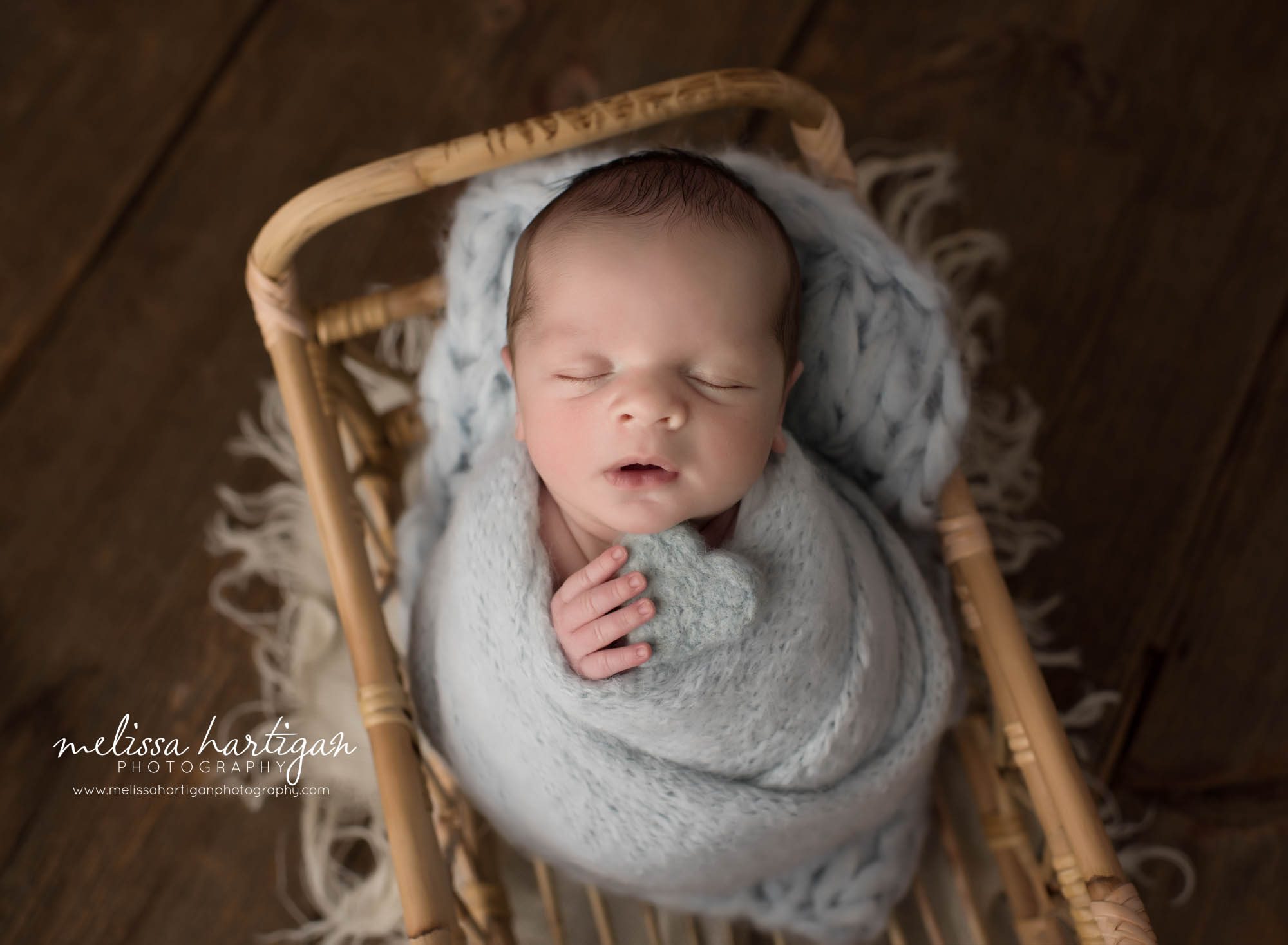 newborn baby boy wrapped in blue wrap posed in basket holding light blue felted heart prop CT newborn photography