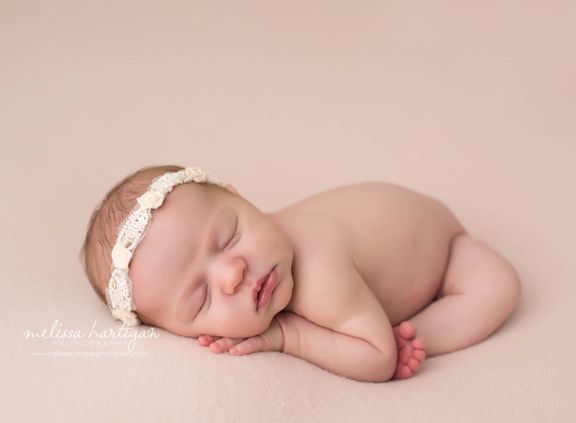 newborn baby girl posed modified taco pose on light pink backdrop