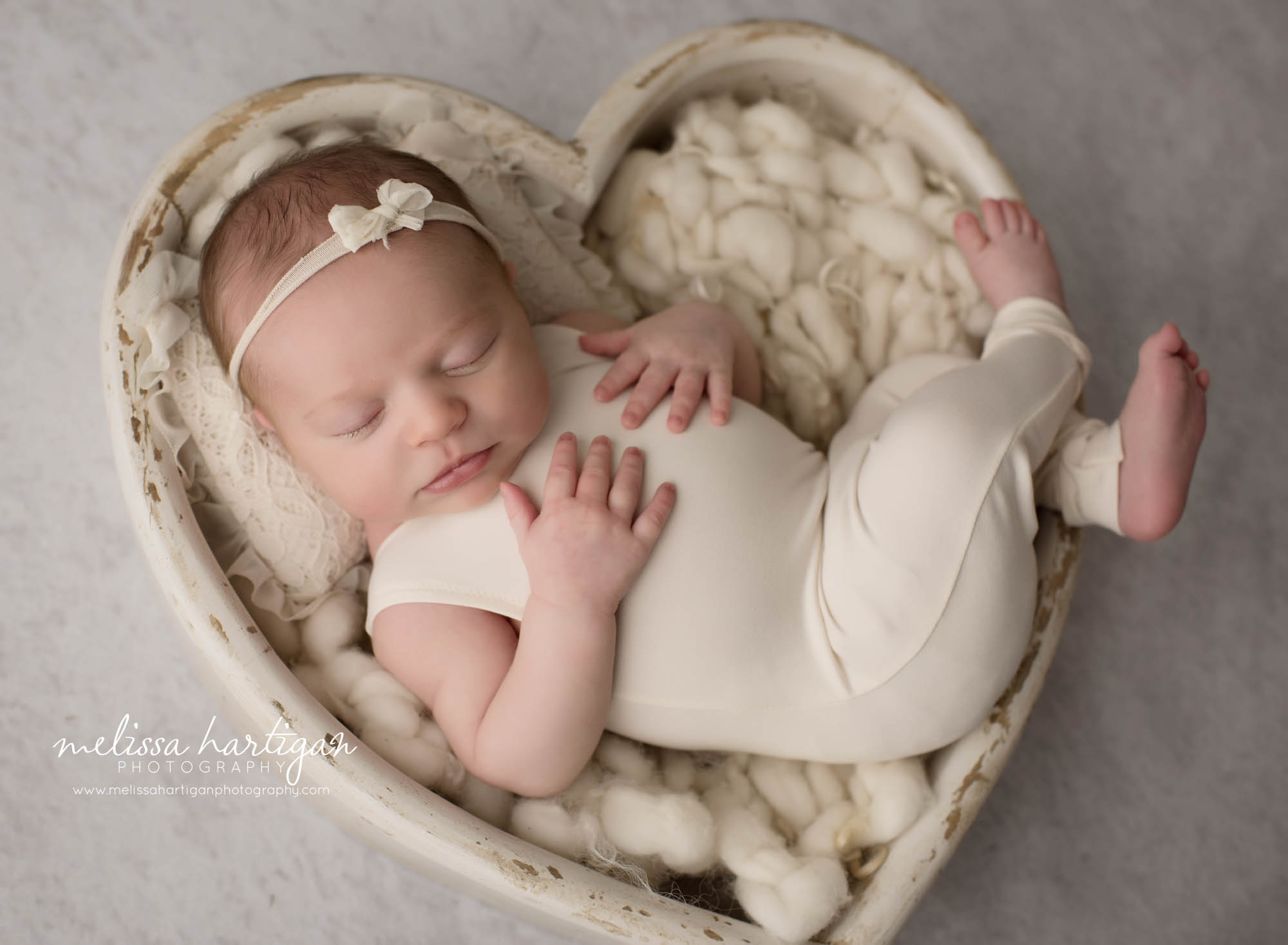 newborn baby girl posed in cream wooden heart bowl prop wearing cream outfit
