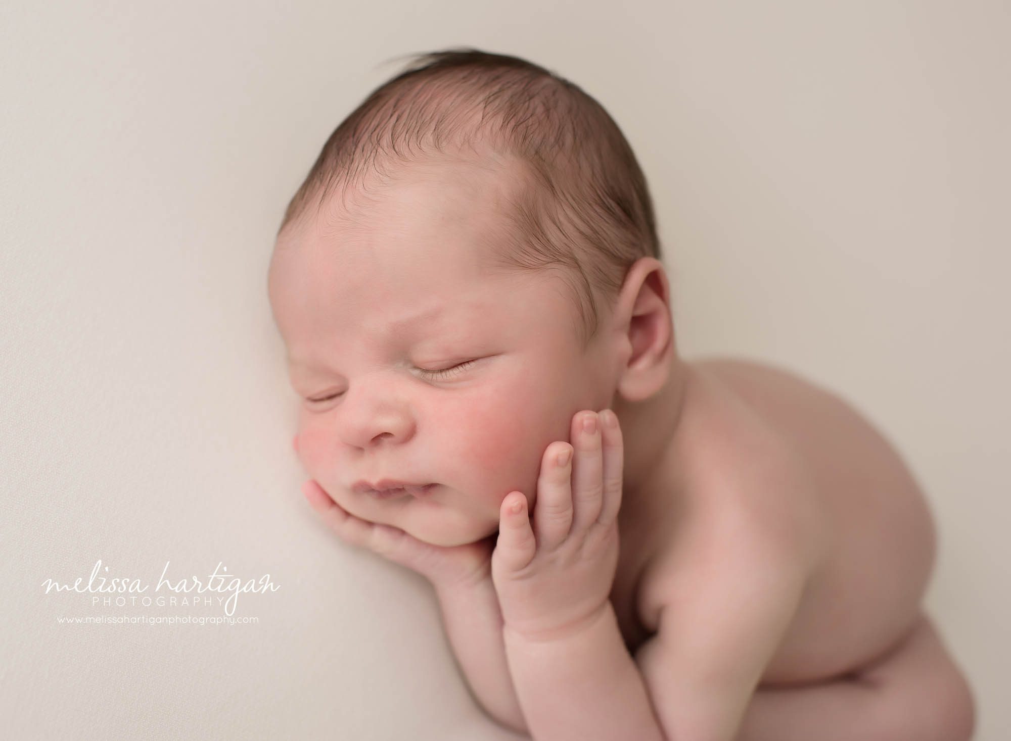 newborn baby boy posed on side with hands under chin