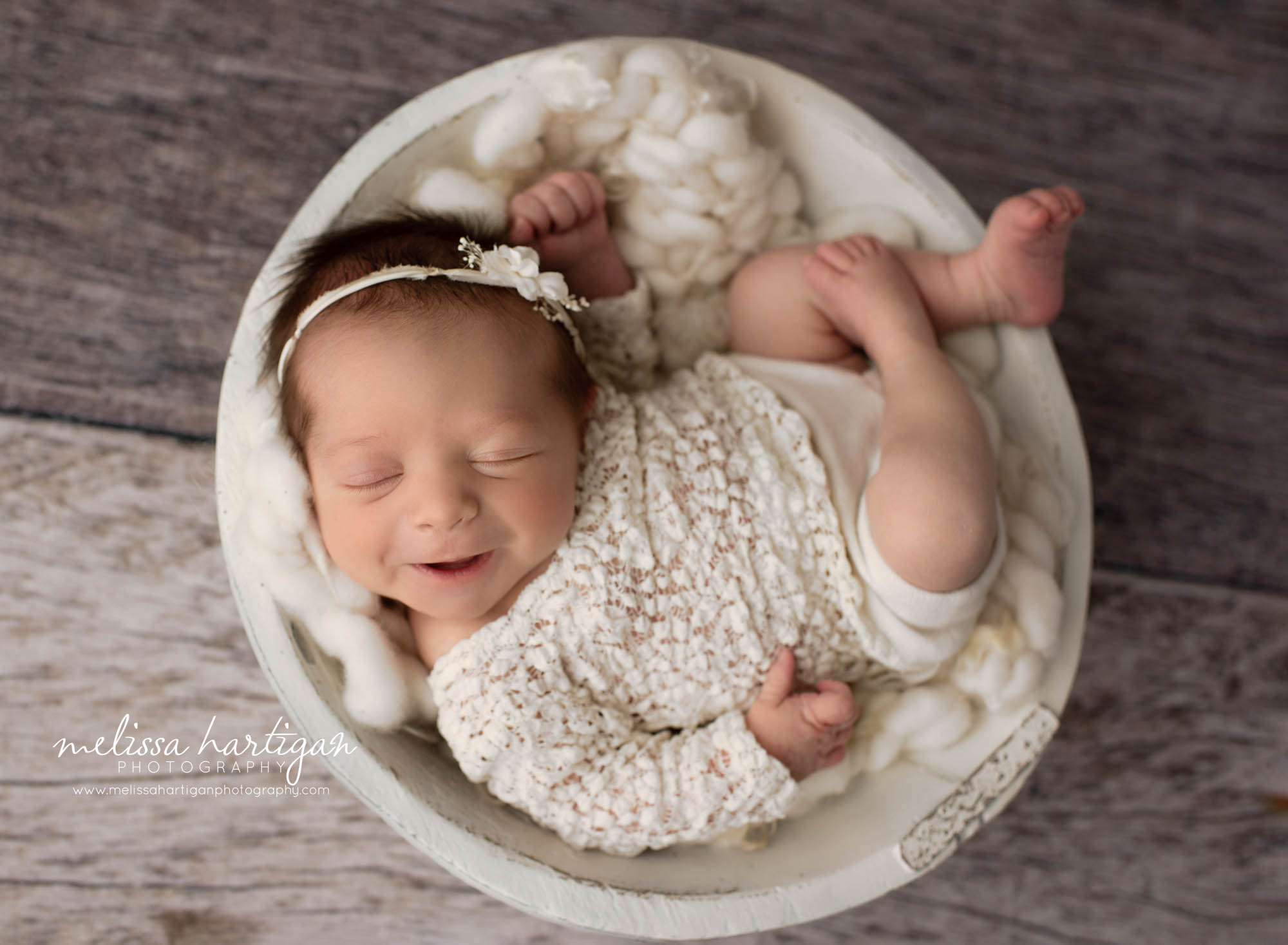 newborn baby girl posed in cream wooden bowl smiling wearing cream newborn girl outfit