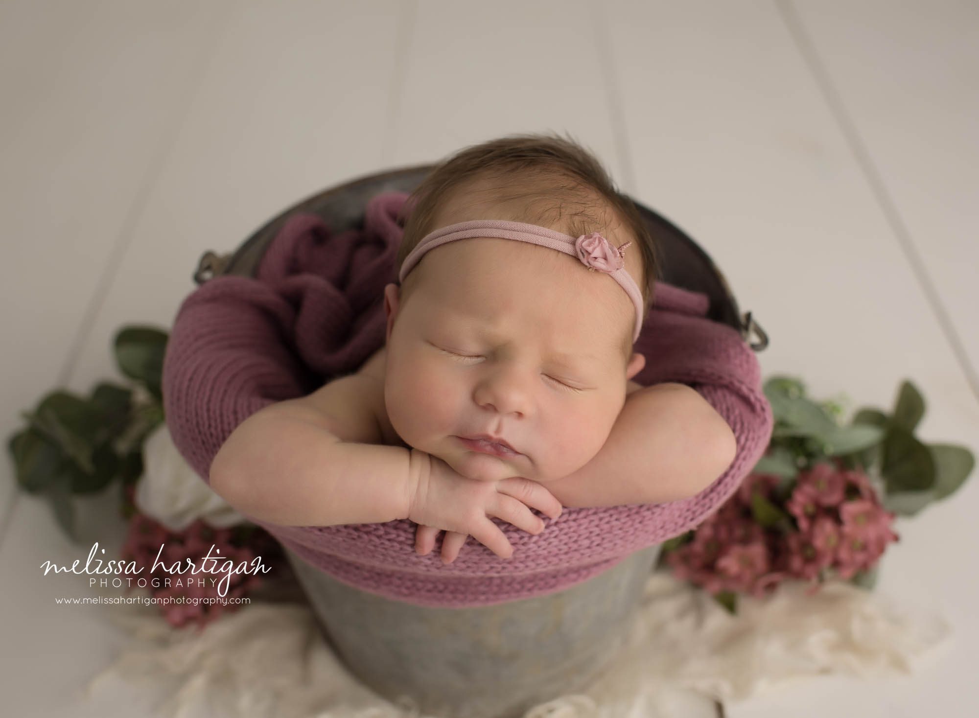 newborn baby girl posed in bucket with rose pink knit wrap and pink bow
