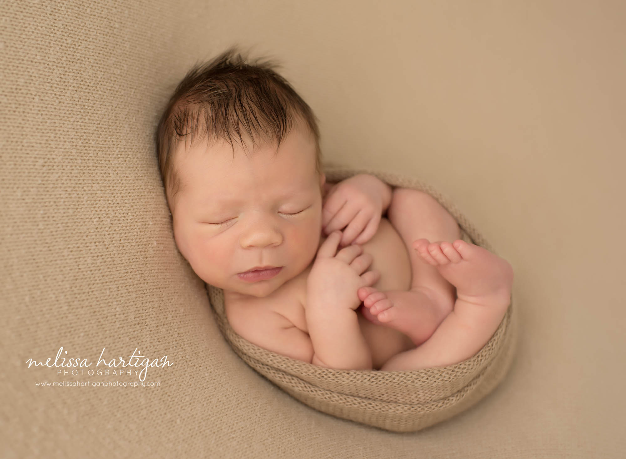 newborn baby boy posed on tan backdrop wrapped in knitted tan colored wrap Avon CT newborn photography 