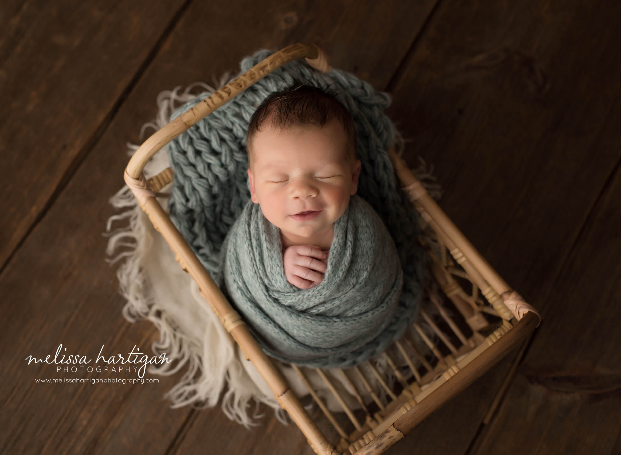 newborn baby boy posed in basket smiley smirking happy baby swaddled in teal