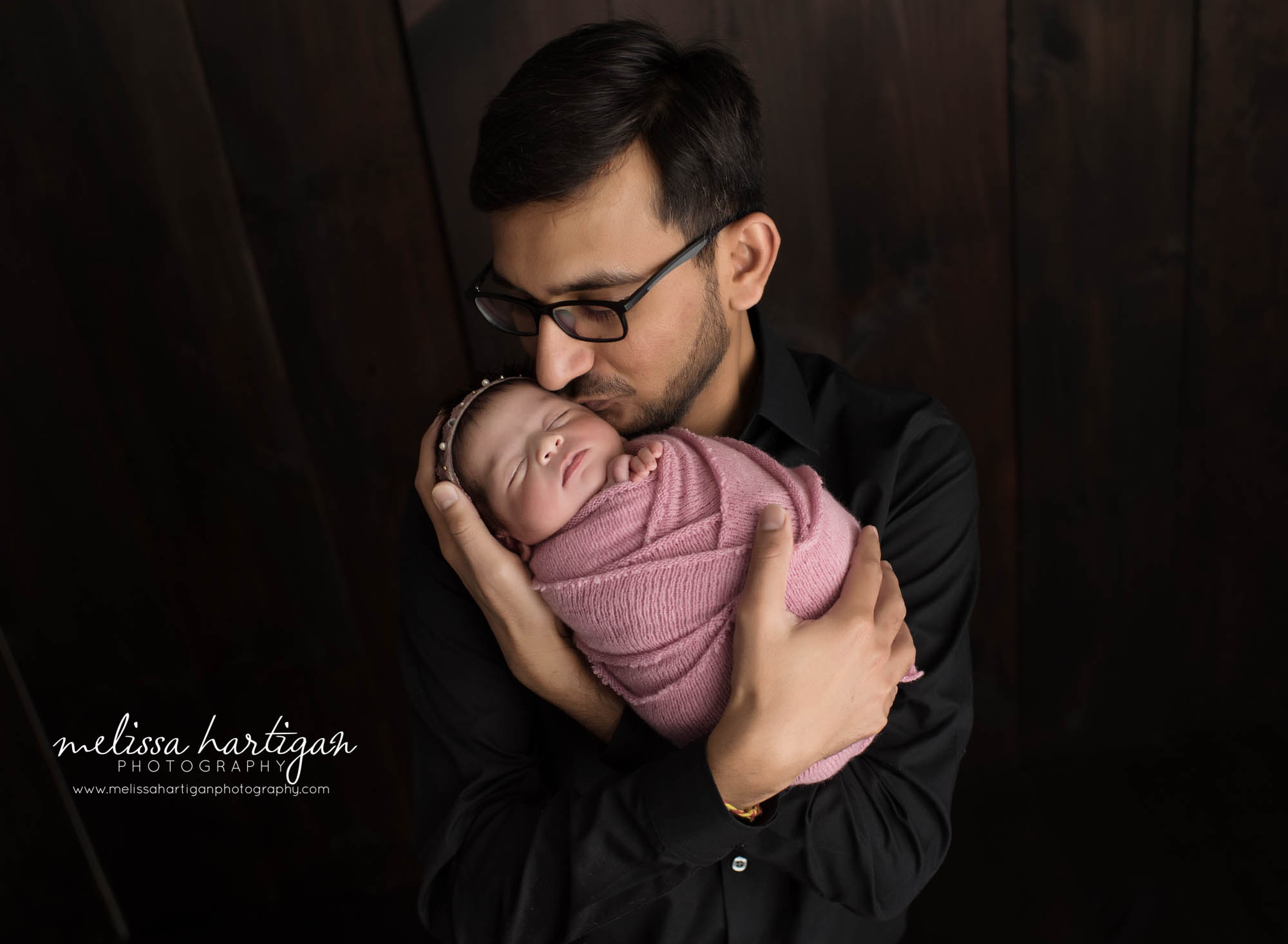 dad holding newborn daughter in parents pose newborn photography