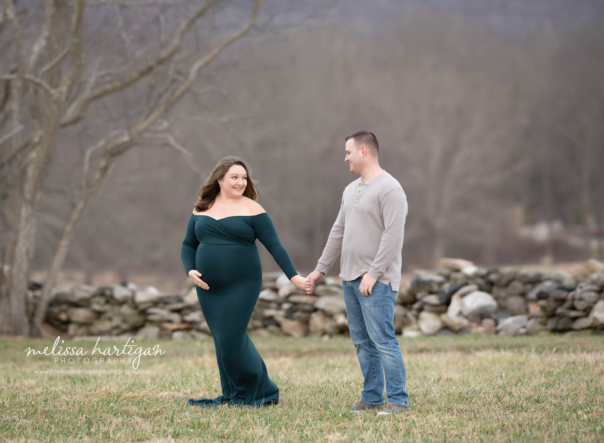 couple holding hands pregnancy standing pose outside Connecticut park