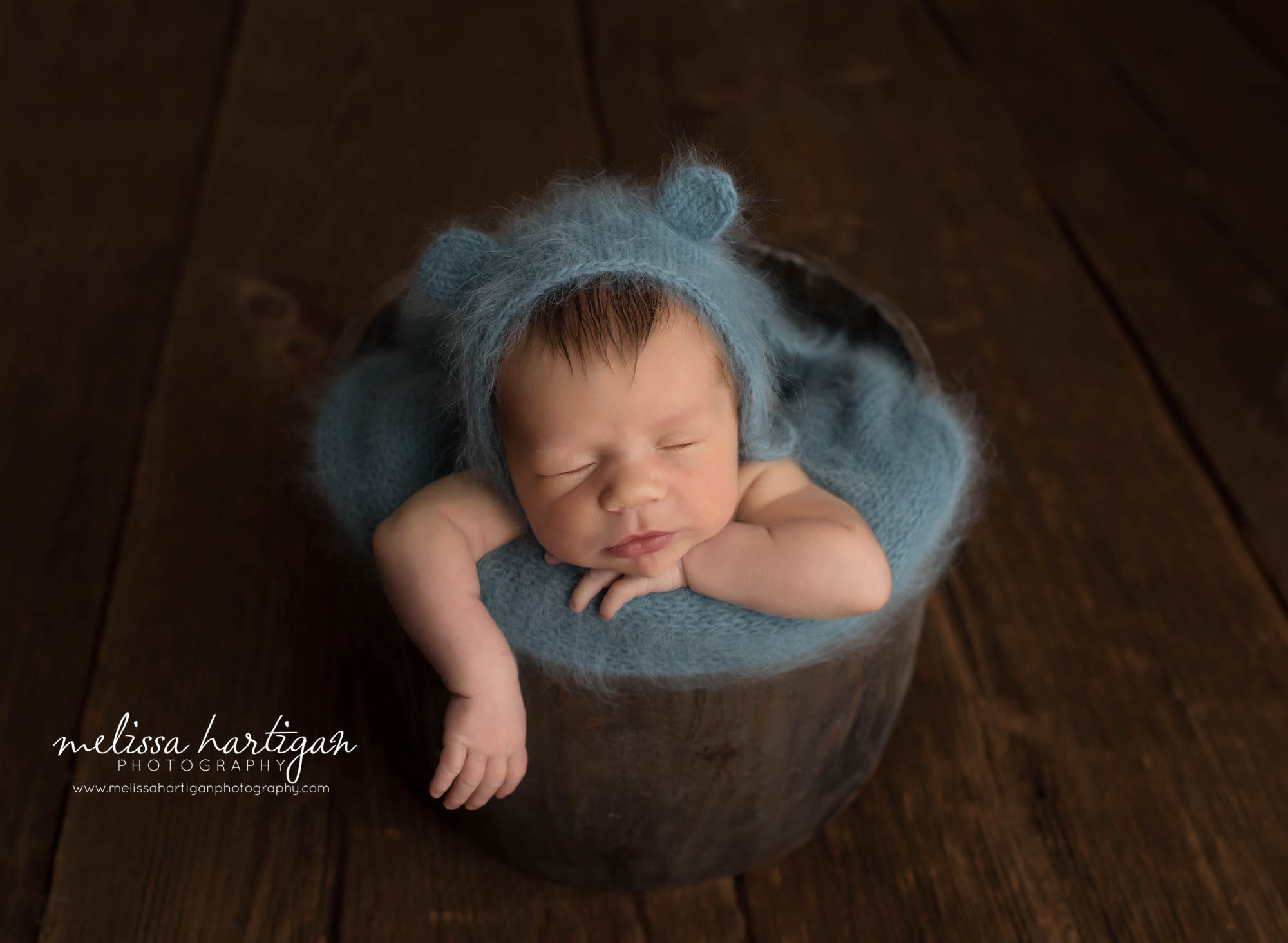 newborn baby boy posed in bucket wearing teal green blue knitted wrap and bear bonnet Newborn photography Avon CT