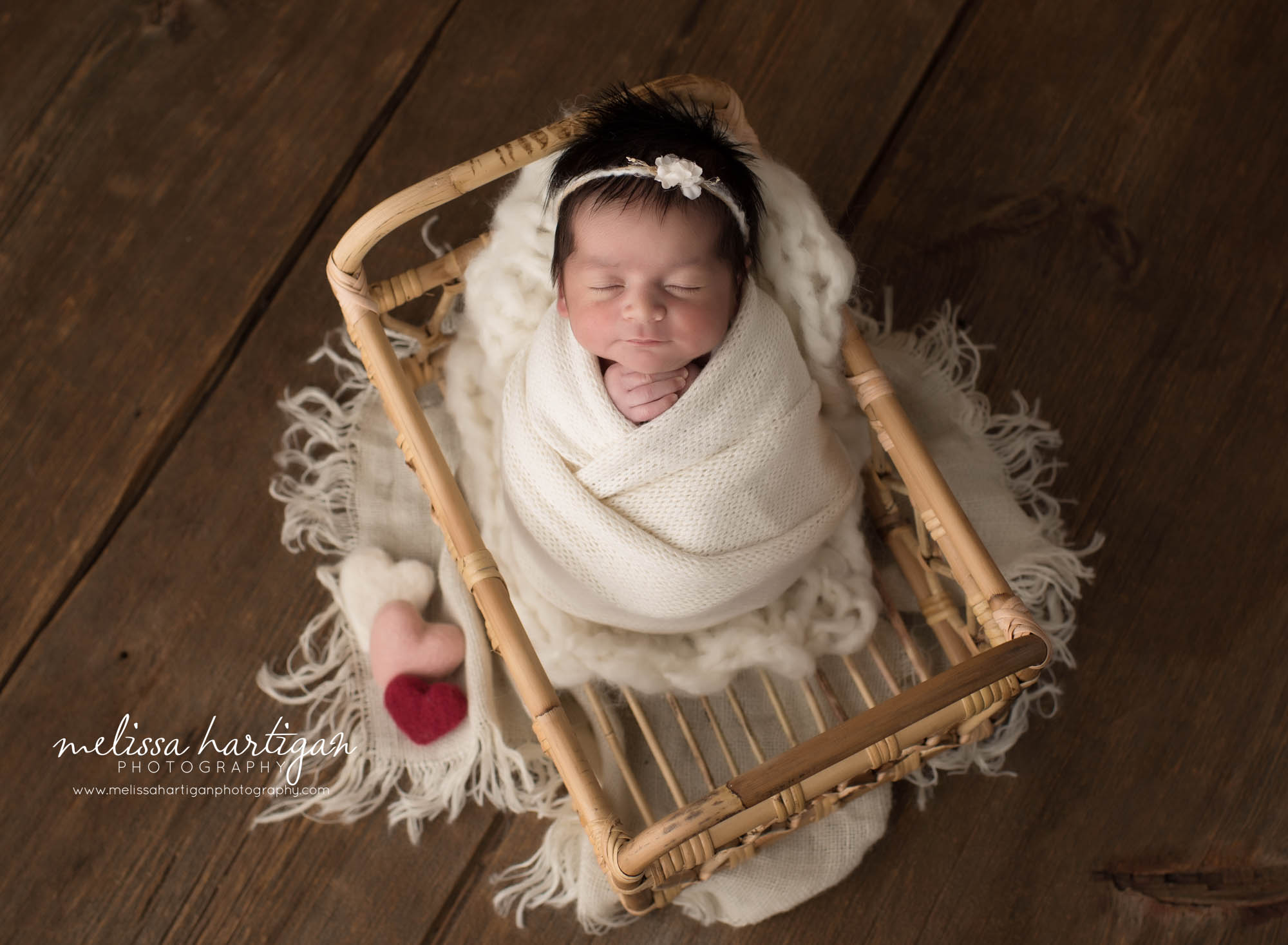newborn baby girl wrapped in cream posed in basket