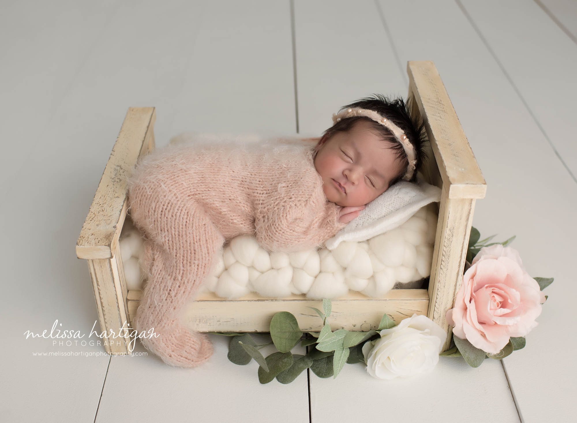 newborn baby girl wearing knitted footed sleeper posed sleeping on cream wooden bed prop windsor locks CT newborn photographer