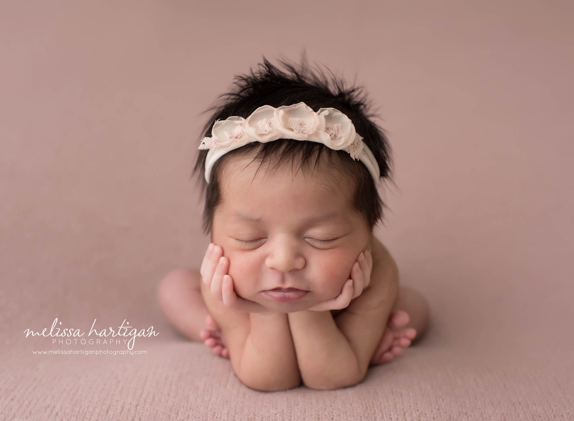 newborn baby girl posed froggy pose on pink backdrop wearing floral headband windsor locks newborn photography
