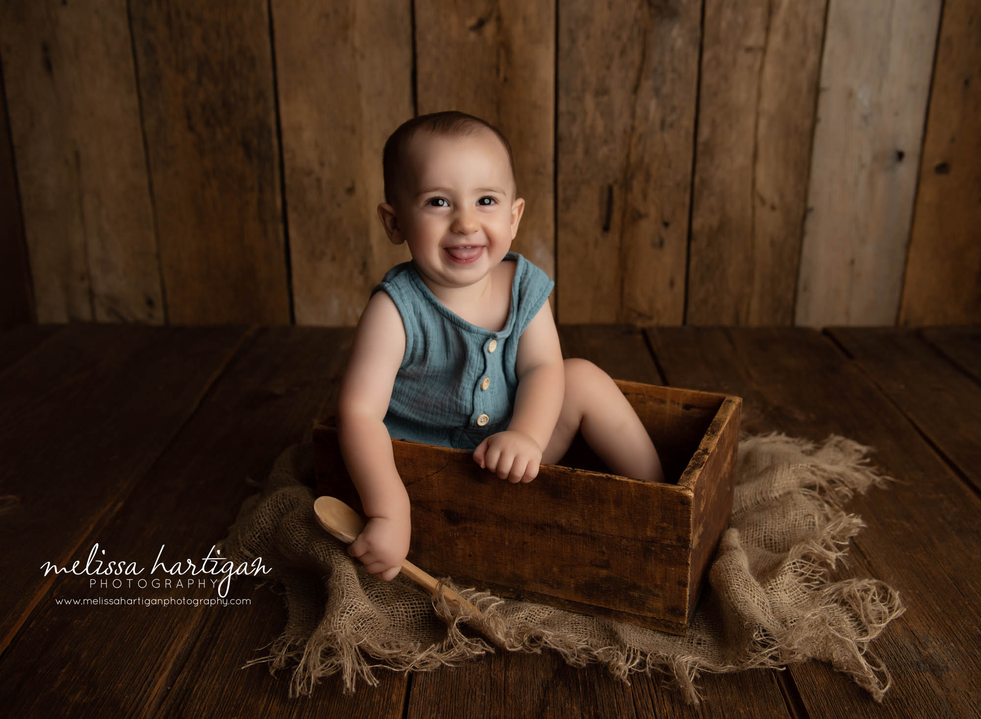 happy smiling baby boy sitting in wooden crate wearing teal colored baby boy outfit CT baby photographer