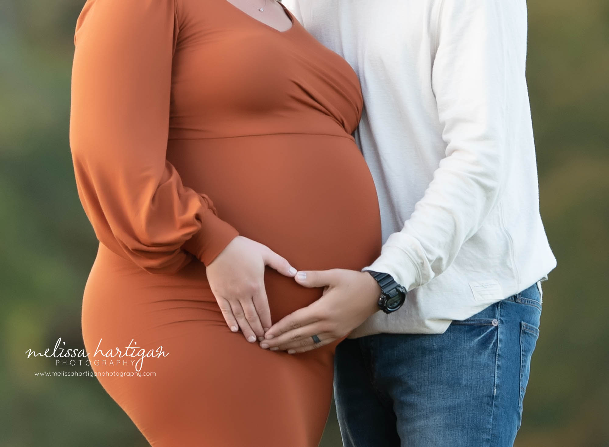 couple holding hands next to baby bump in shape of heart maternity photographer CT