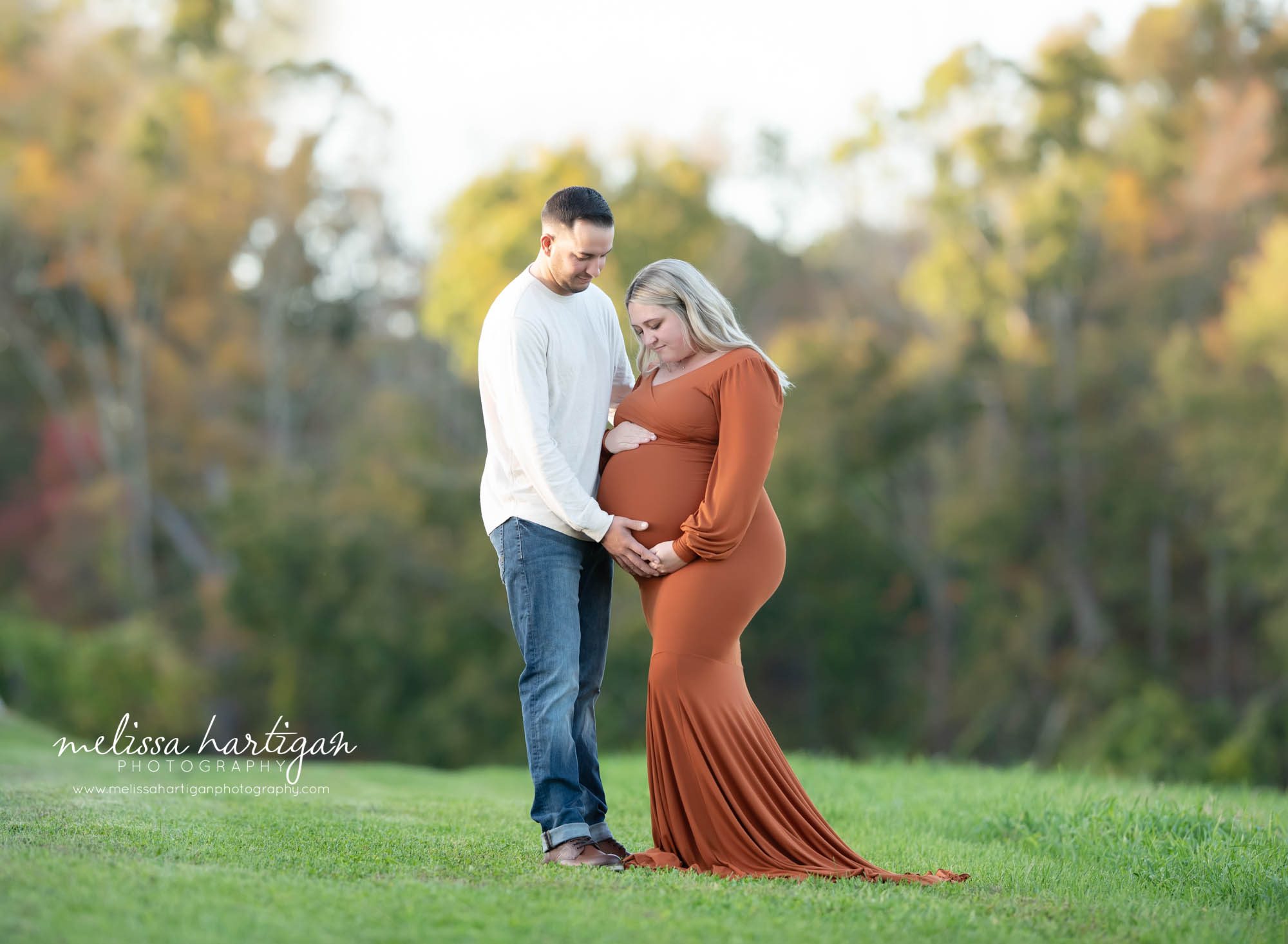 couple expecting baby standing together holding looking down at baby bump maternity photography CT