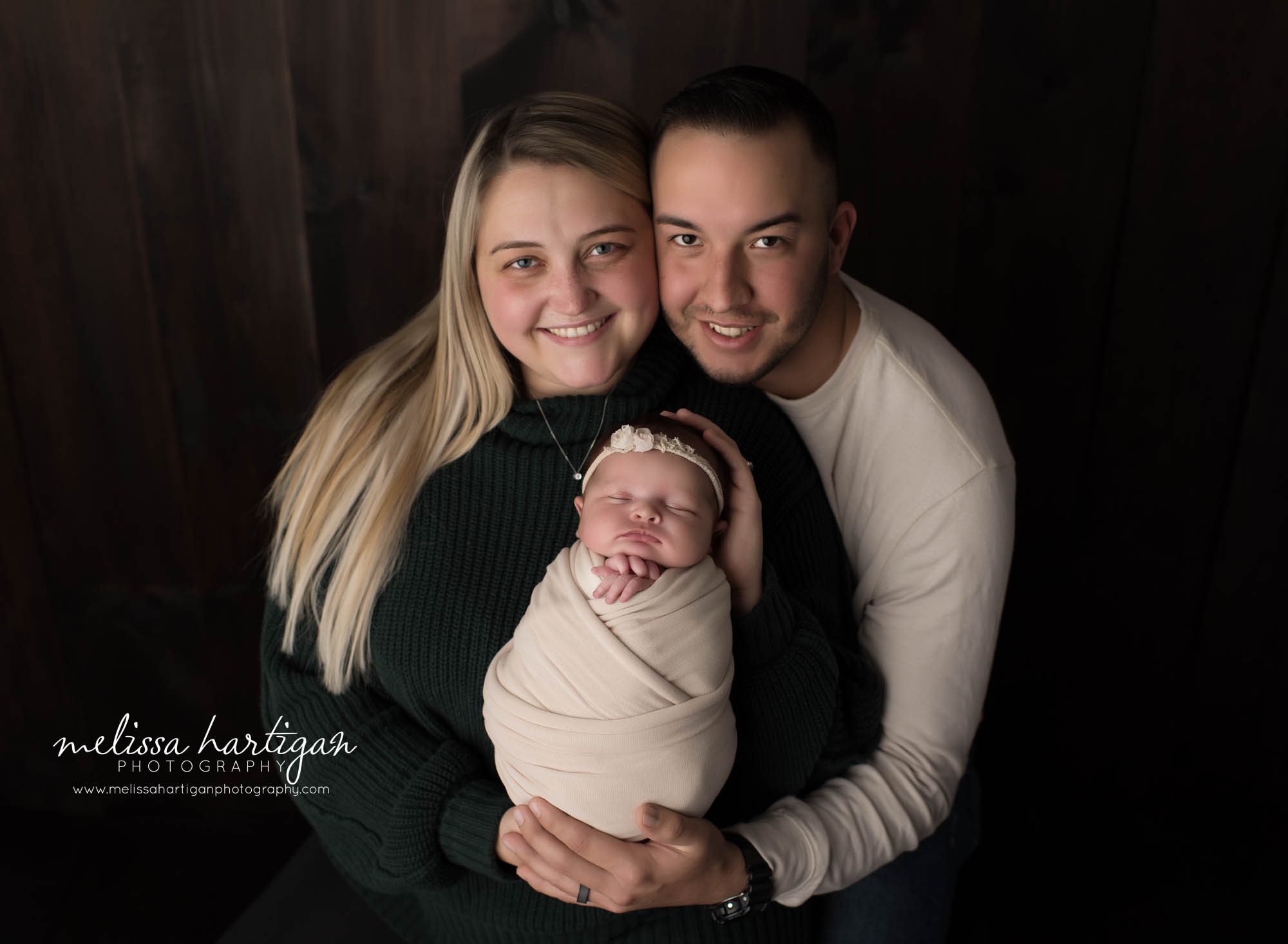 mom dad holding newborn daughter wrapped in cream colored wrap family pose newborn photography CT MA
