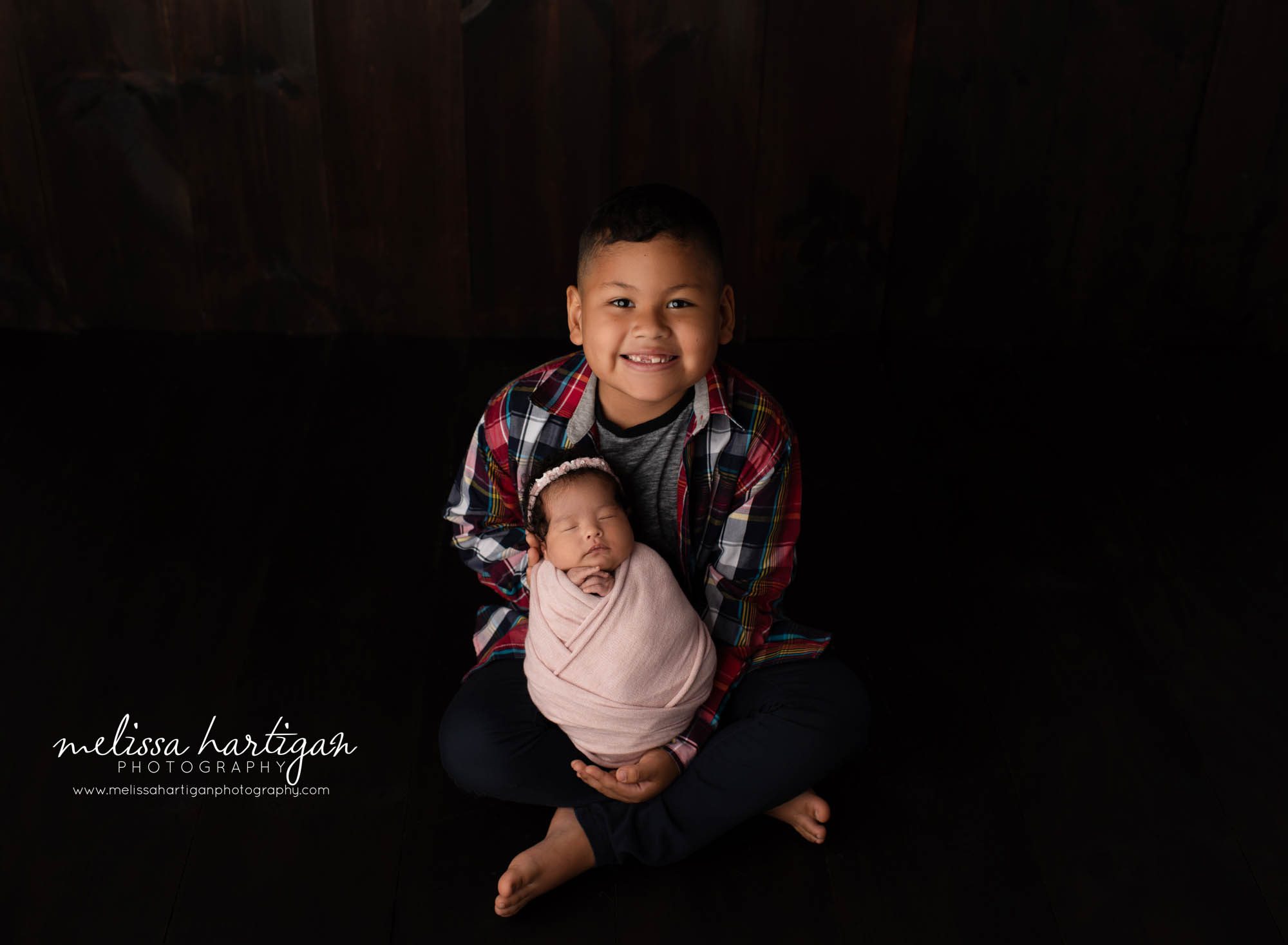 big brother holding newborn sister wrapped in pink wrap smiling happy brother Connecticut newborn photographer