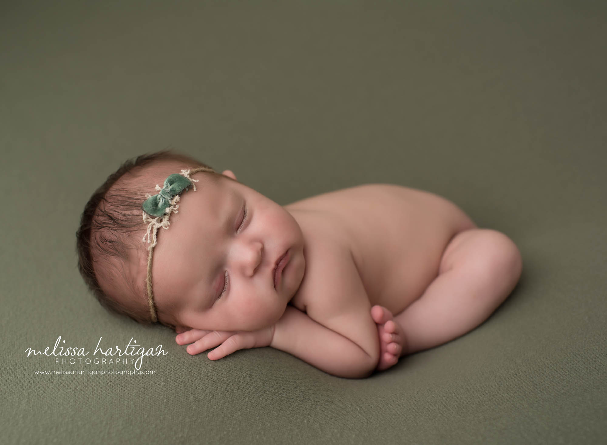 newborn baby girl posed on green backdrop in modified taco pose newborn photography