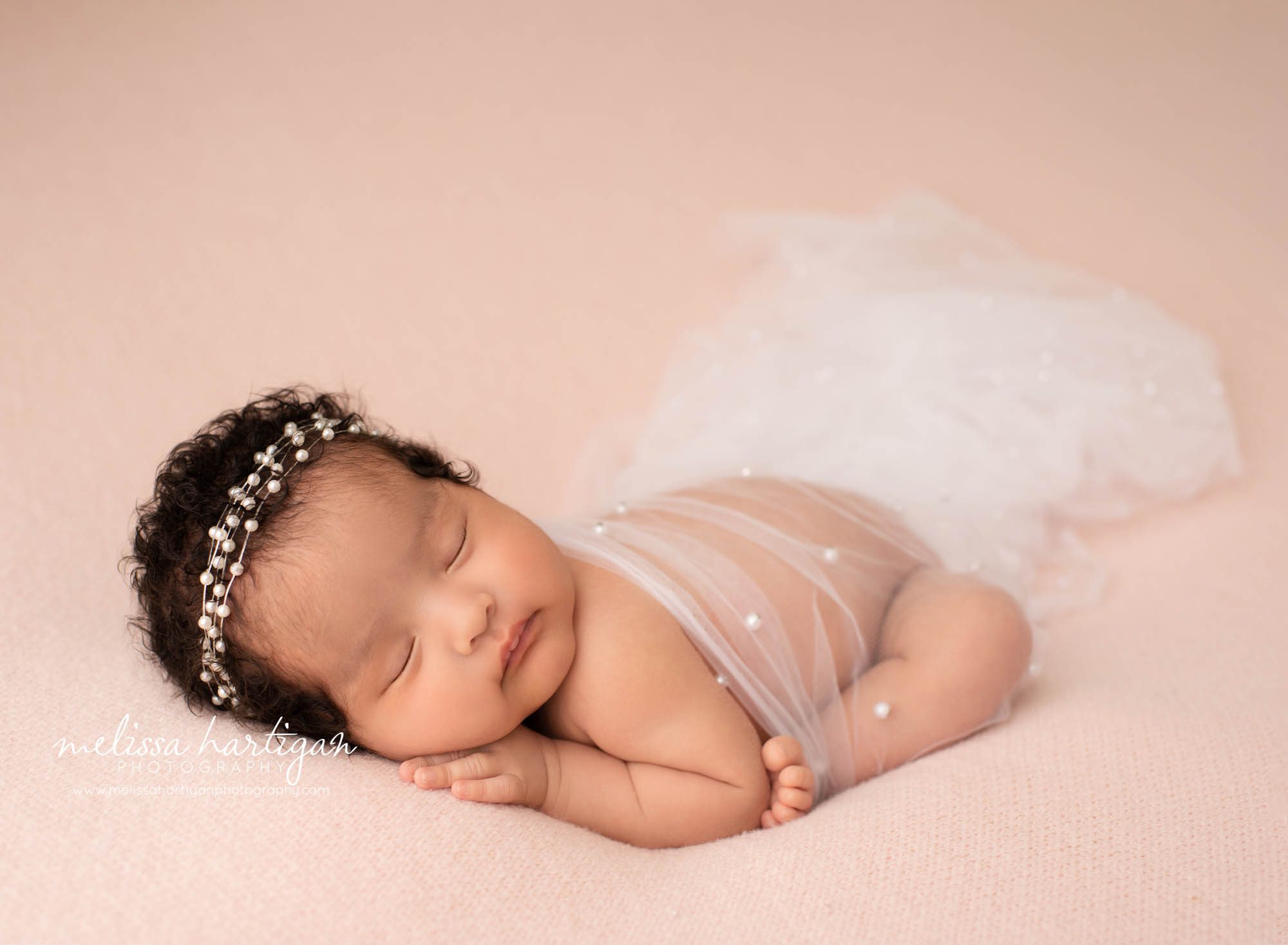 newborn baby girl posed on pink backdrop wearing beaded bandband newborn photographer east hartford