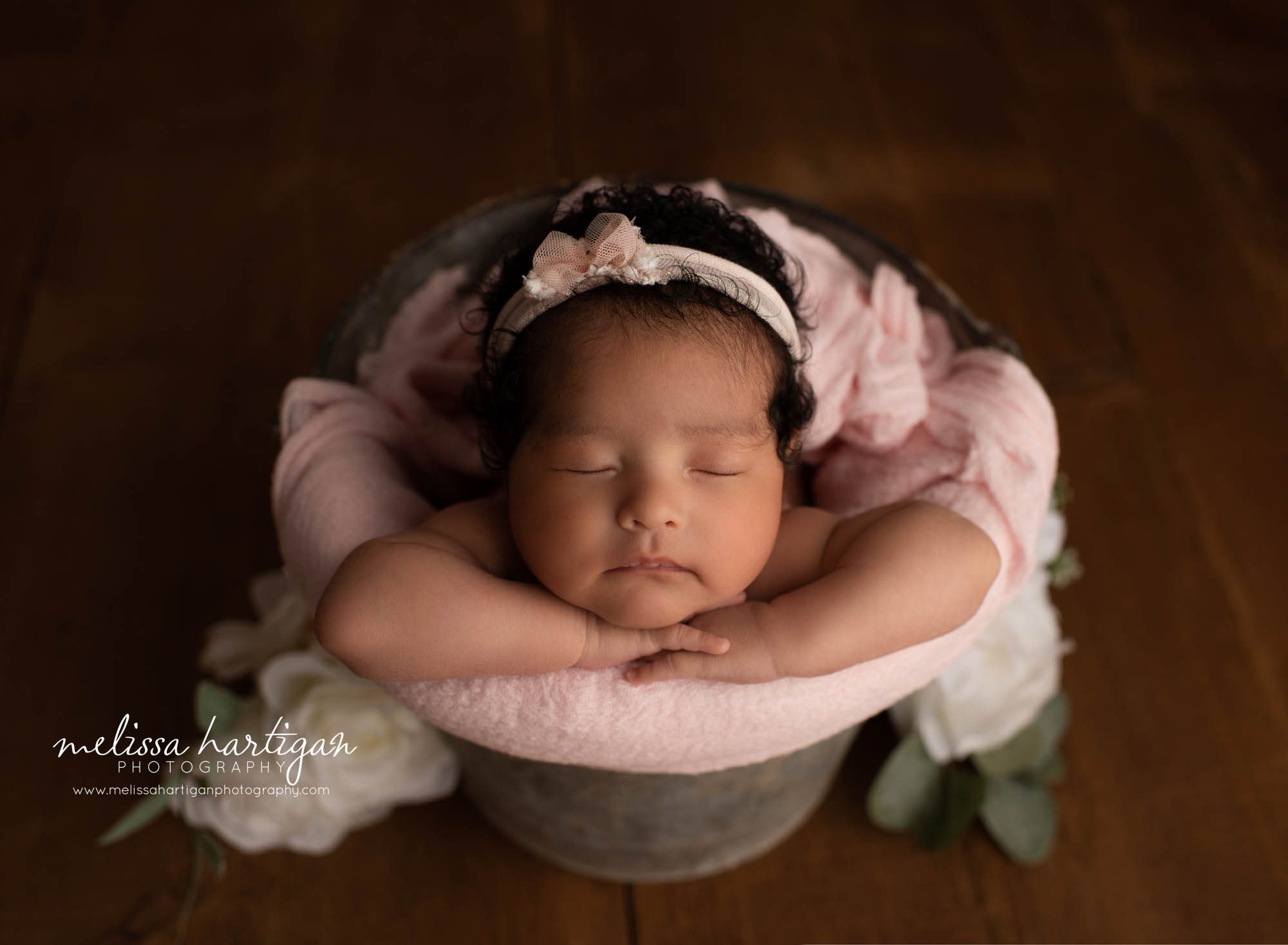 newborn baby girl posed in bucket wearing pink headband newborn photographer 