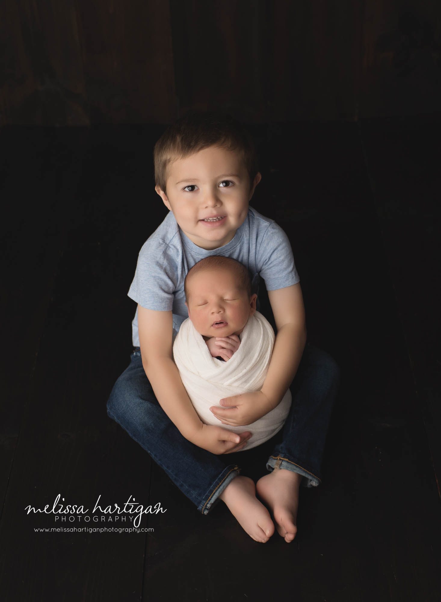 newborn baby boy wrapped in cream wrap being held by big brother in sibling pose newborn photography Ellington CT