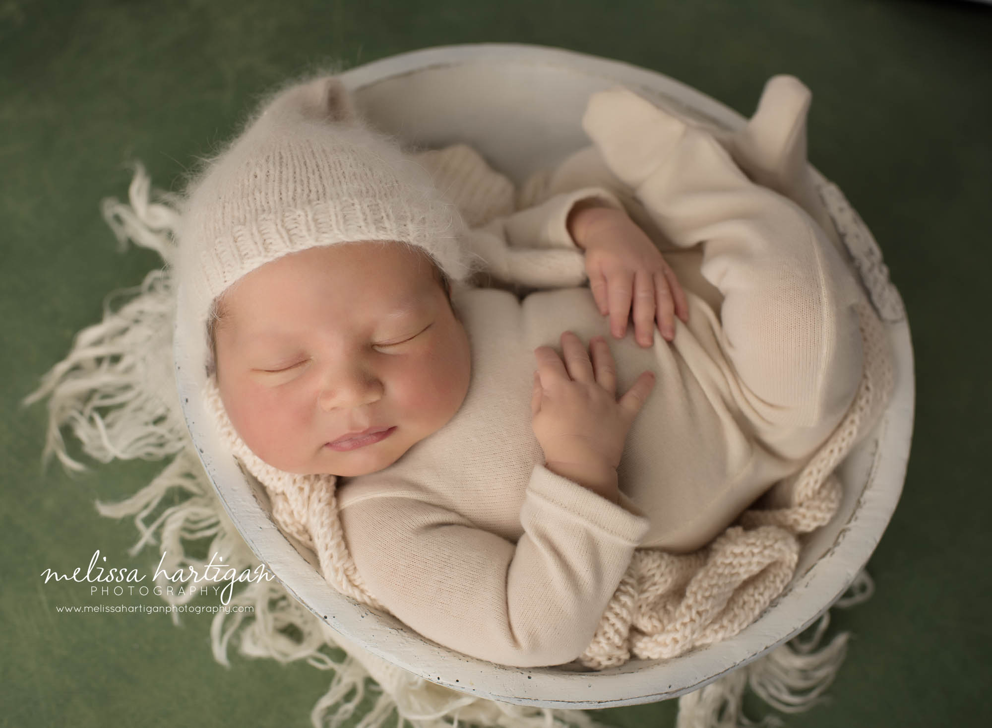 newborn baby boy posed in wooden cream bowl wearing cream newborn boy outfit