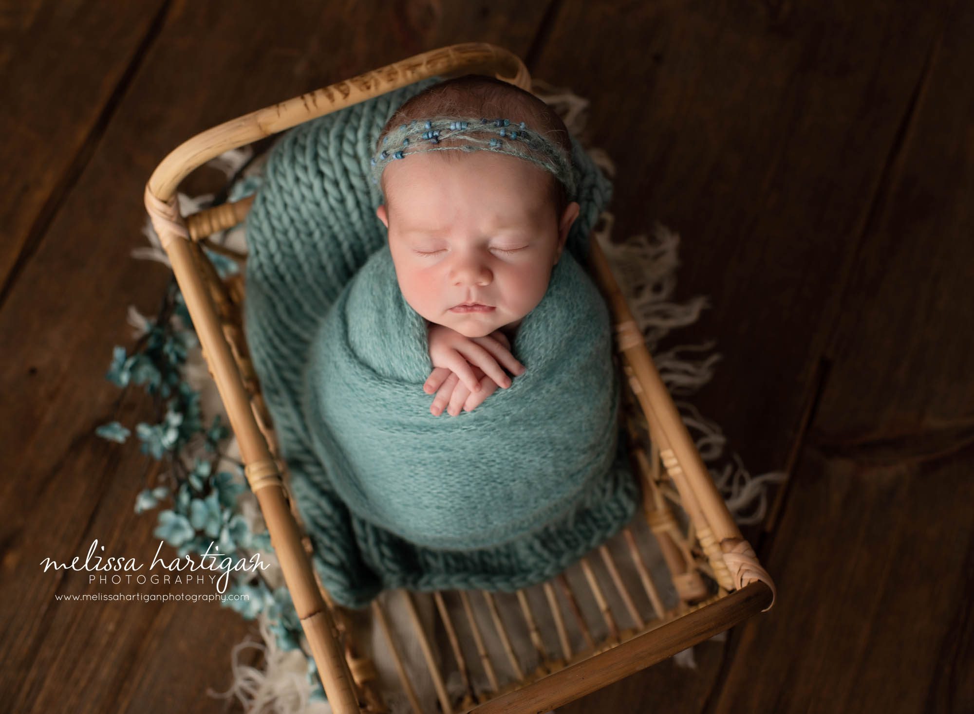 newborn baby girl wrapped in turquoise knitted wrap posed in basket newborn photography hartford county