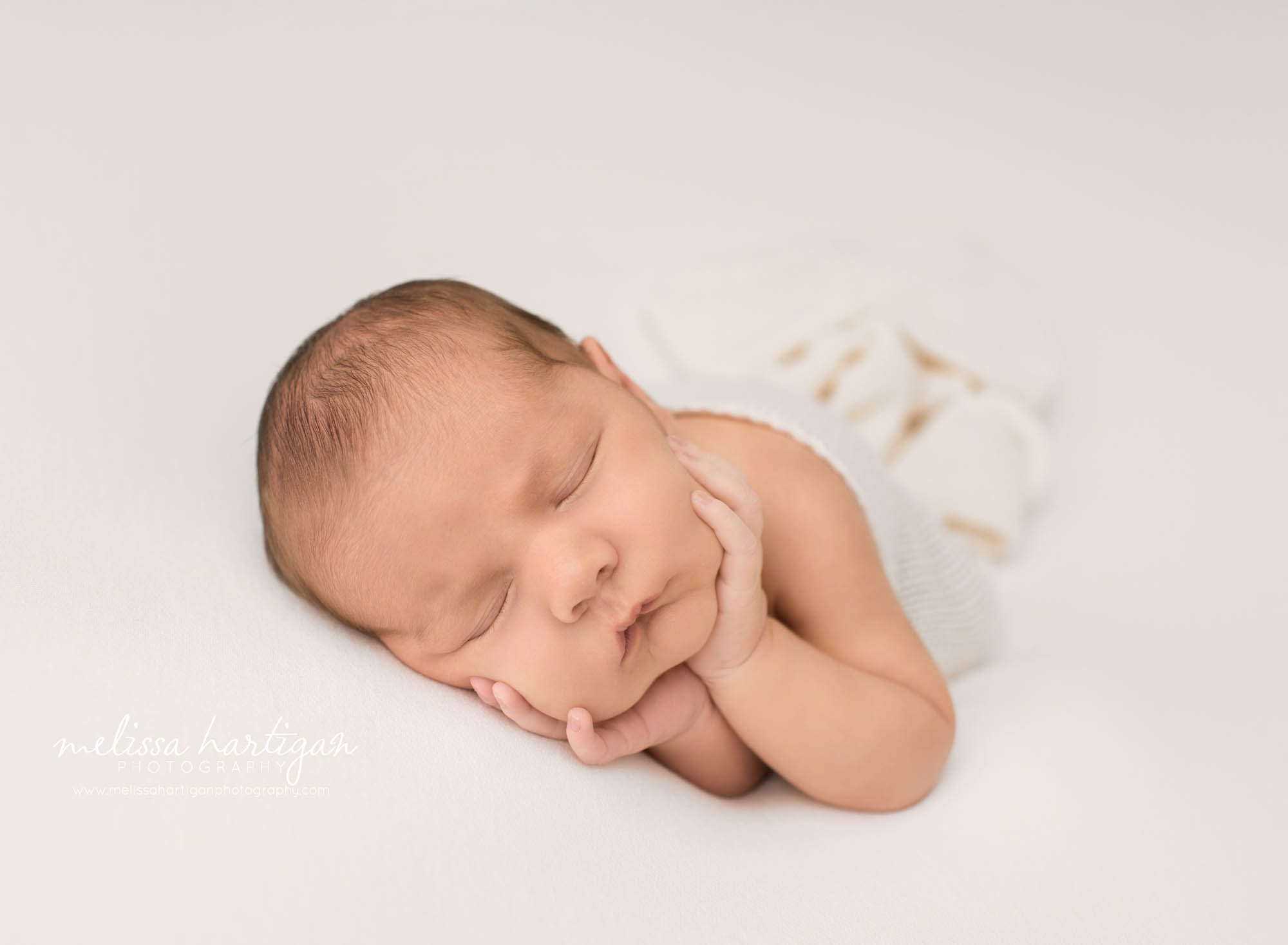 newborn baby boy posed on side with hands holding cheeks baby photography CT