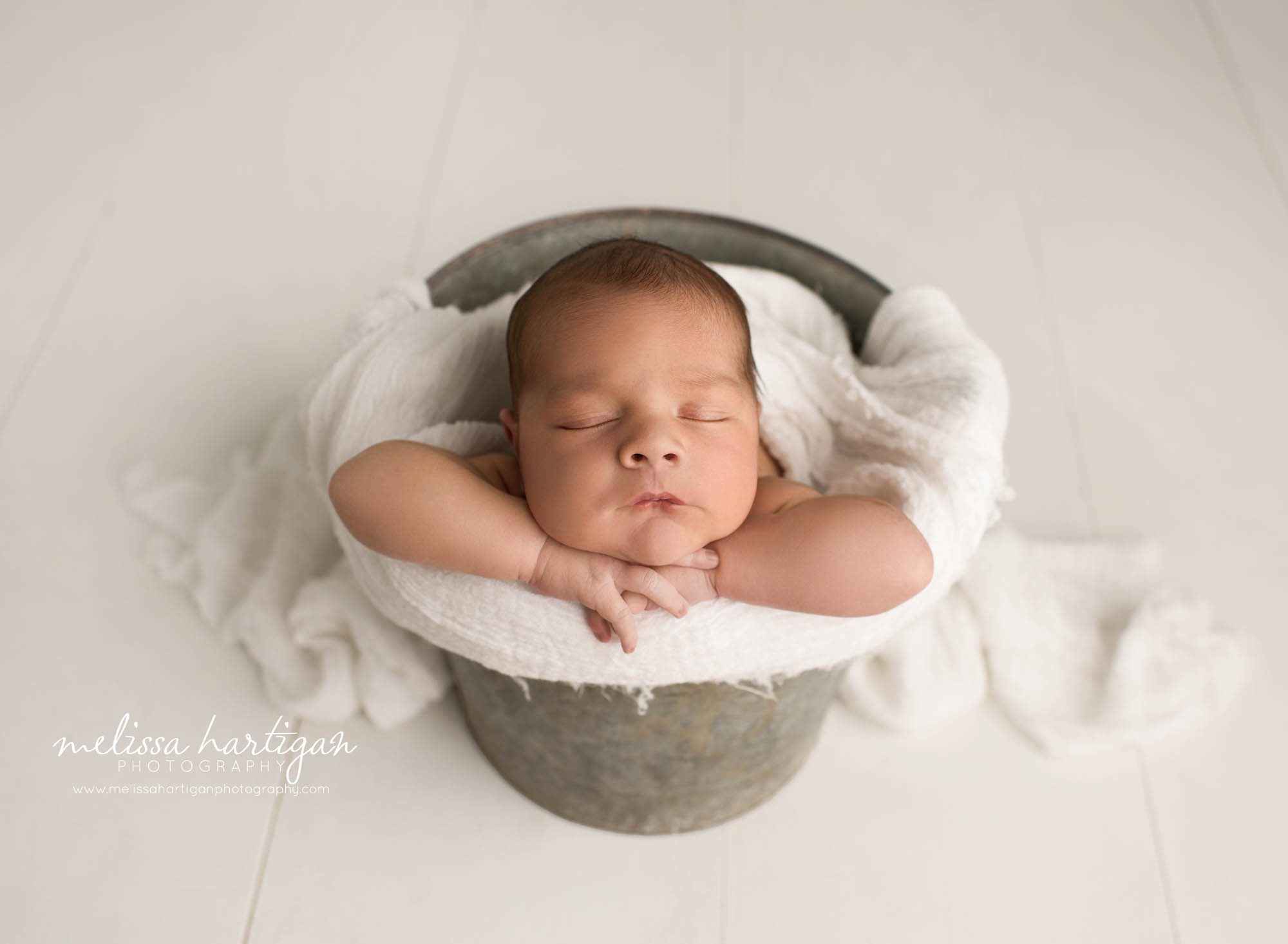 newbonr baby boy posed in metal bucket with white layer