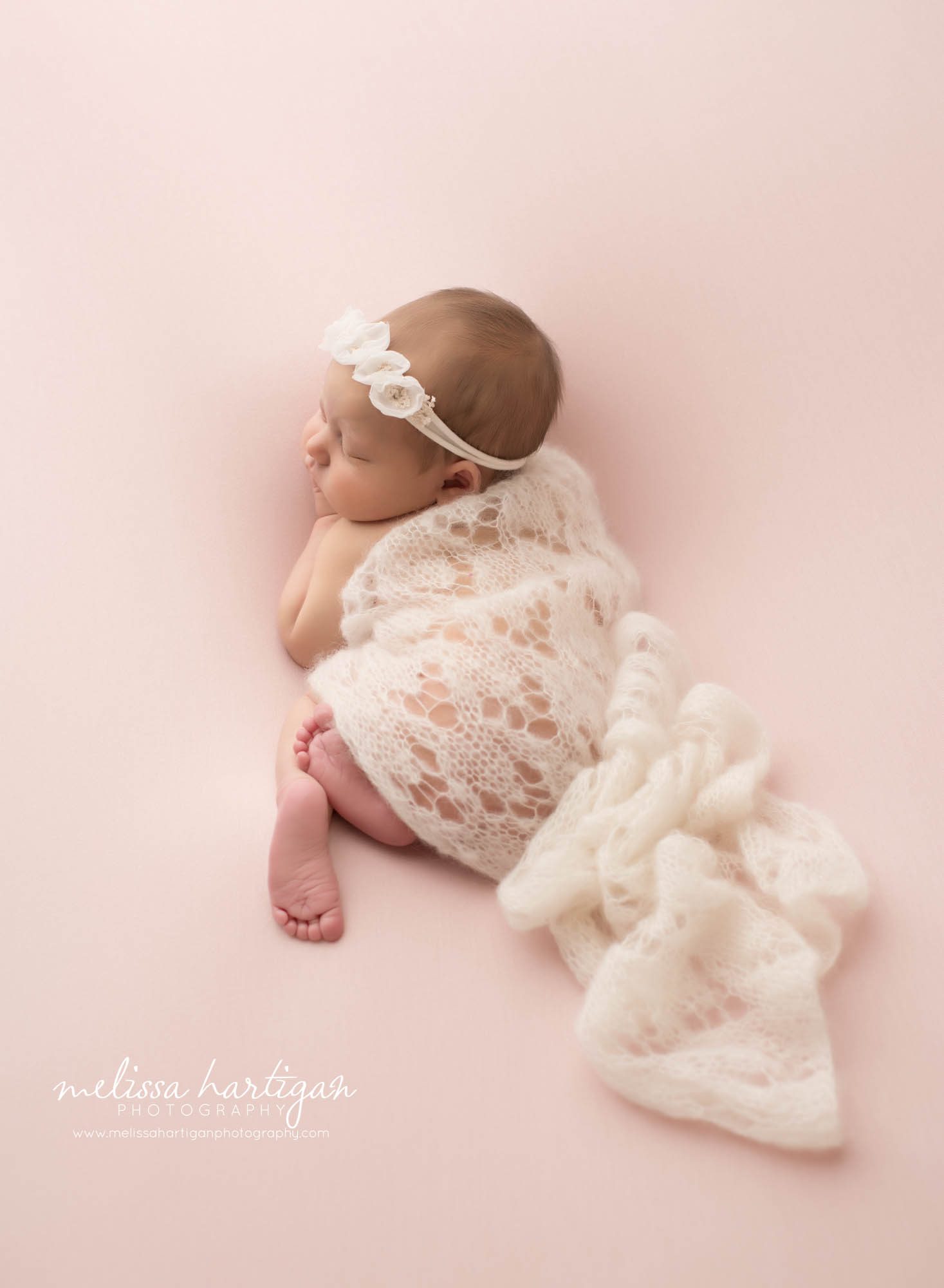 newborn baby girl posed on pink backdrop with knit lace wrap