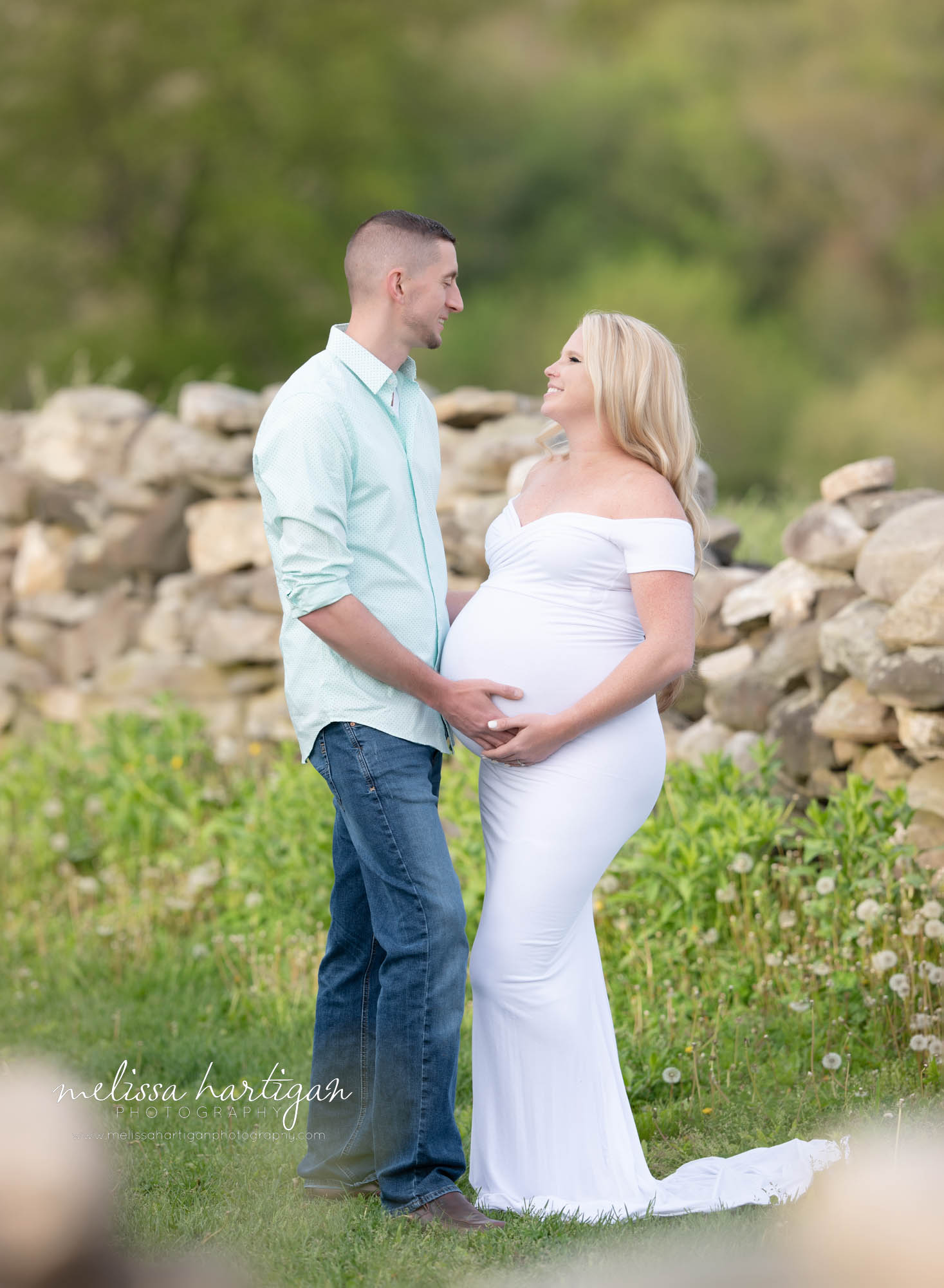 expectant couple holding baby bump standing facing each other