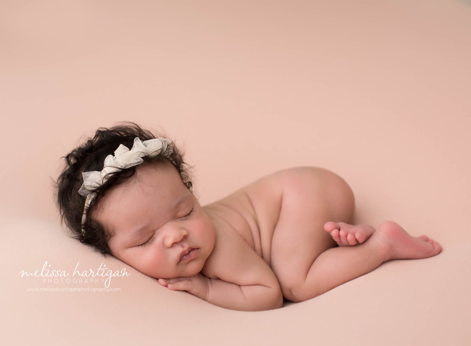 newborn baby girl posed on tummy wearing cream bow headband newborn photography connecticut