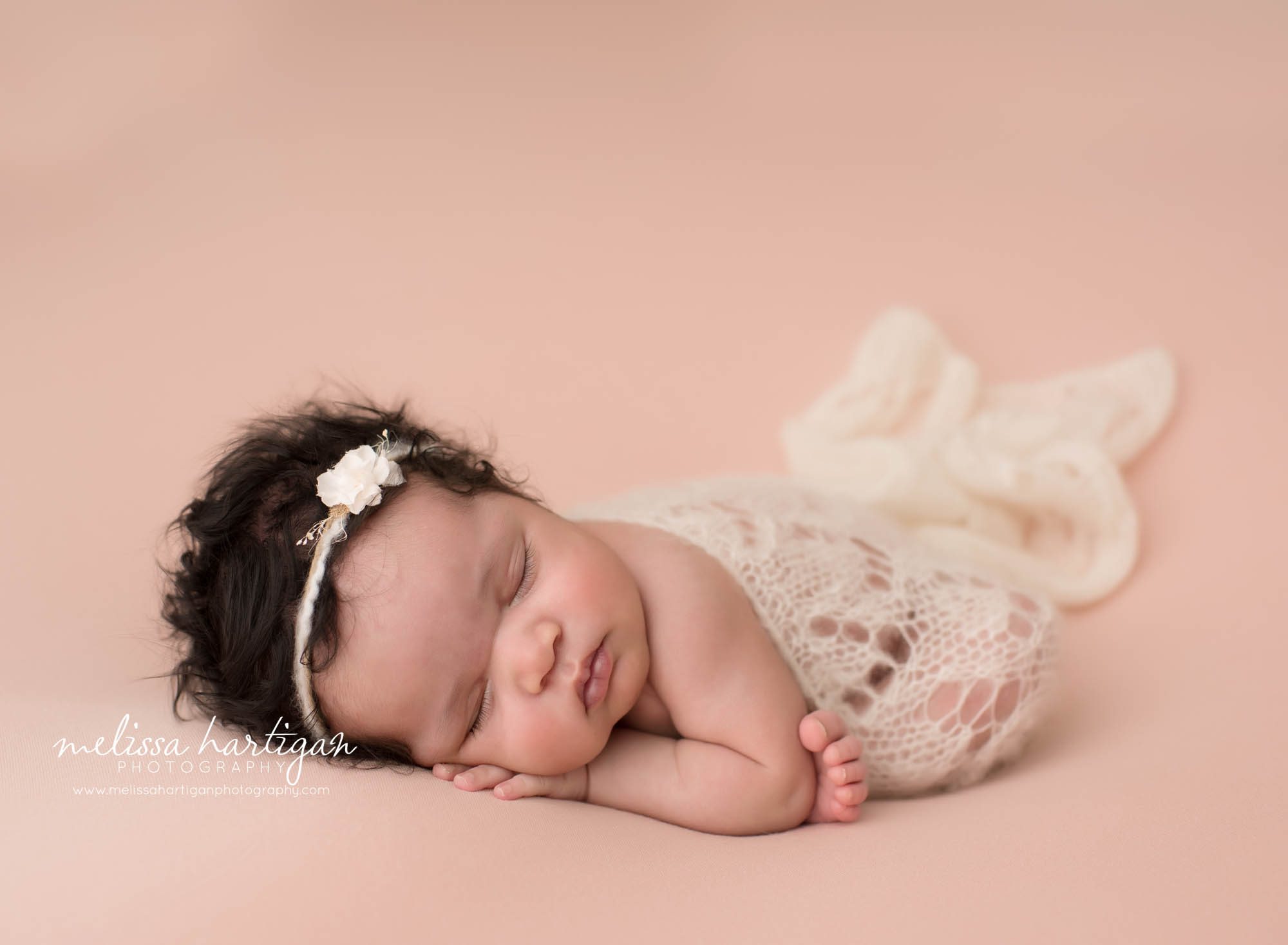 baby girl posed on pink backdrop posed modified taco pose wearing knitted lace wrap and cream headband