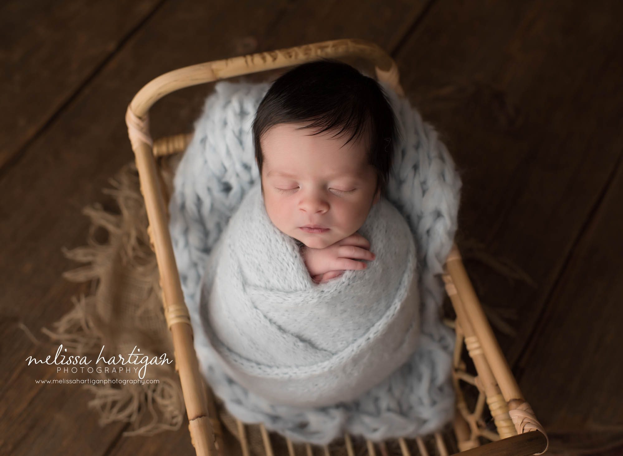newborn baby boy wrapped in gray knitted wrap posed in basket