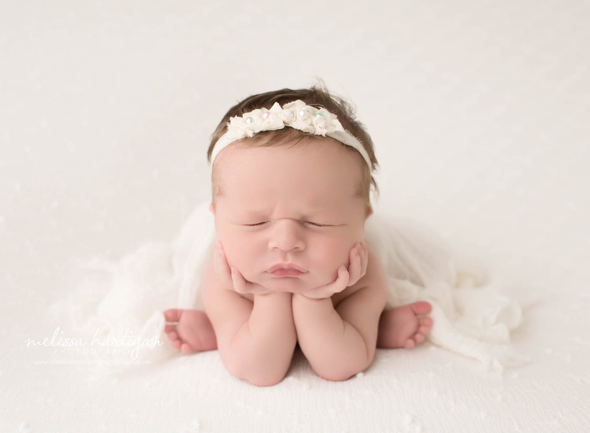 newborn baby girl posed on cream backdrop in froggy pose newborn photography windham county