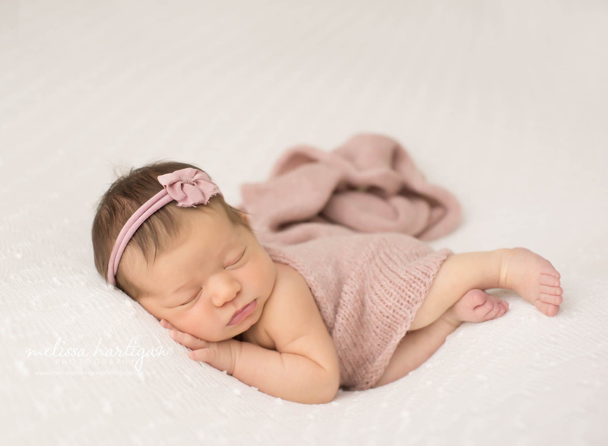 newborn baby girl posed on side with pink knitted wrap draped over wearing pink headband somers CT newborn photographer