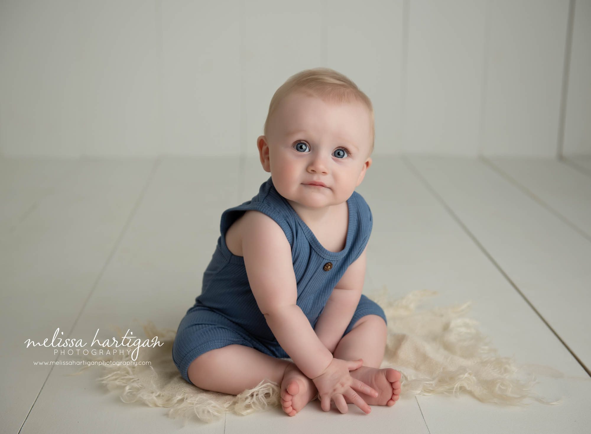 baby boy sitting on wooden boards in studio baby photography session