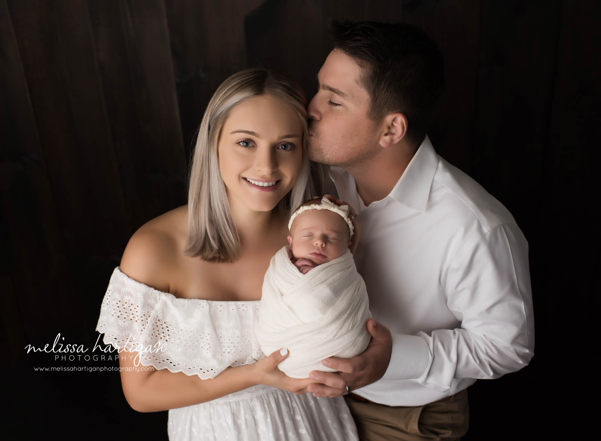 dad kissing mom newborn family photography pose in CT studio