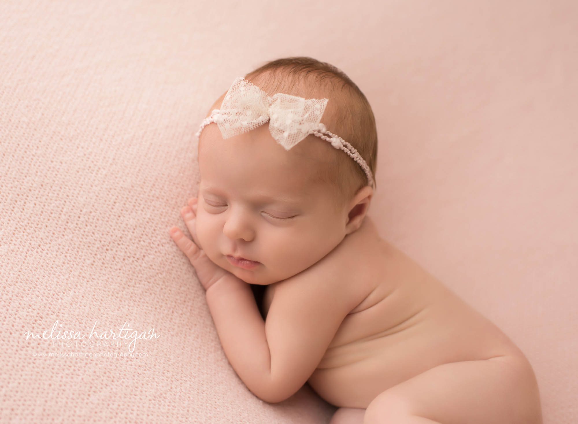 newborn baby girl posed on pink backdrop on side with hand under cheek CT newborn photography