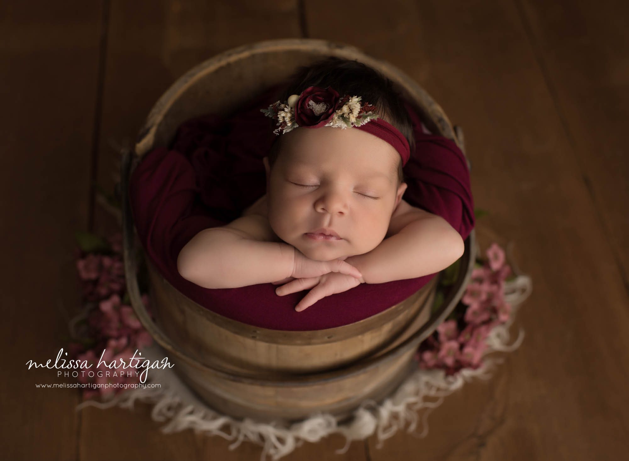 newborn baby girl posed in bucket wearing headband