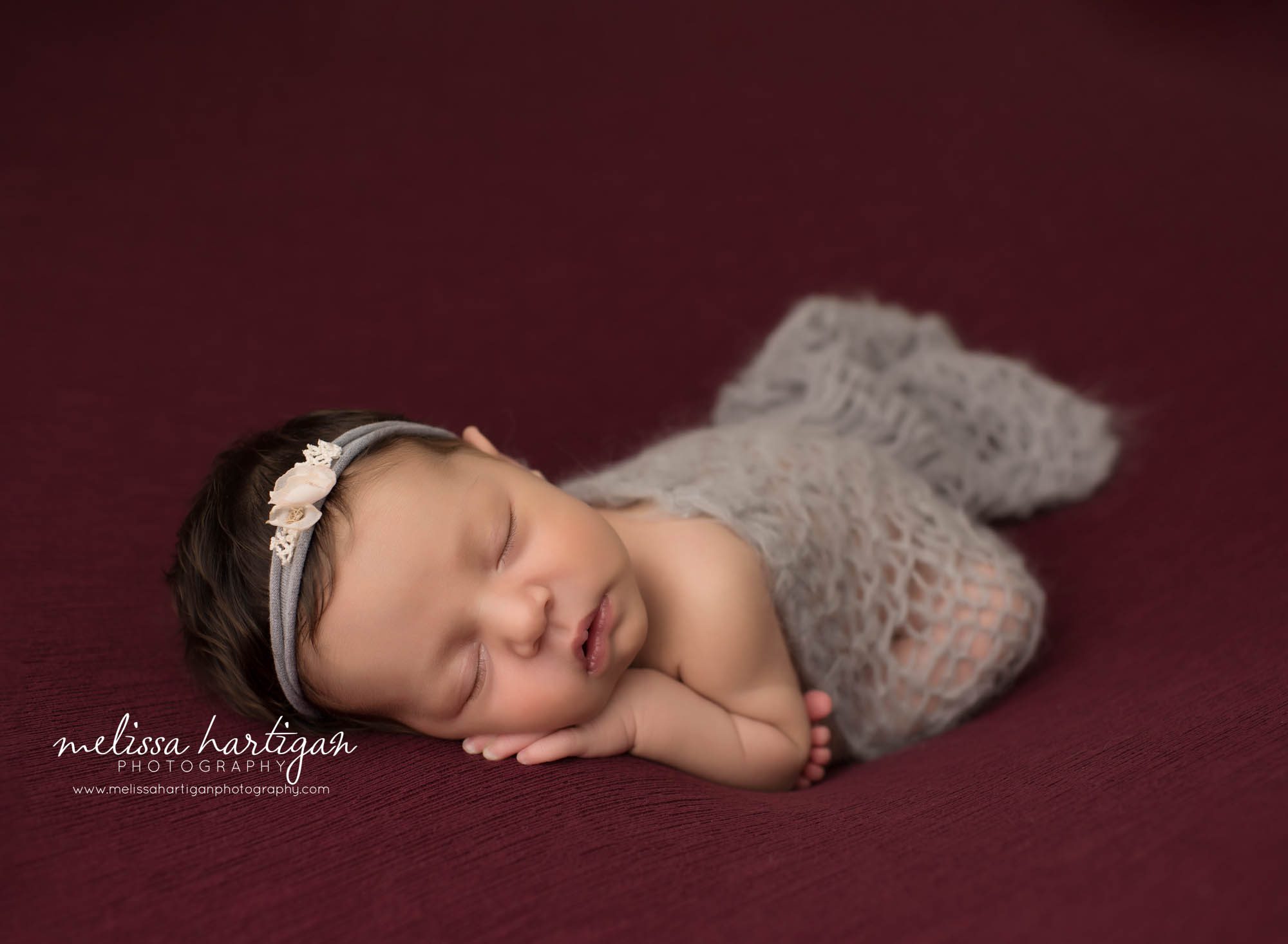 newborn baby girl posed taco pose wearing gray knitted lace wrap draped over her