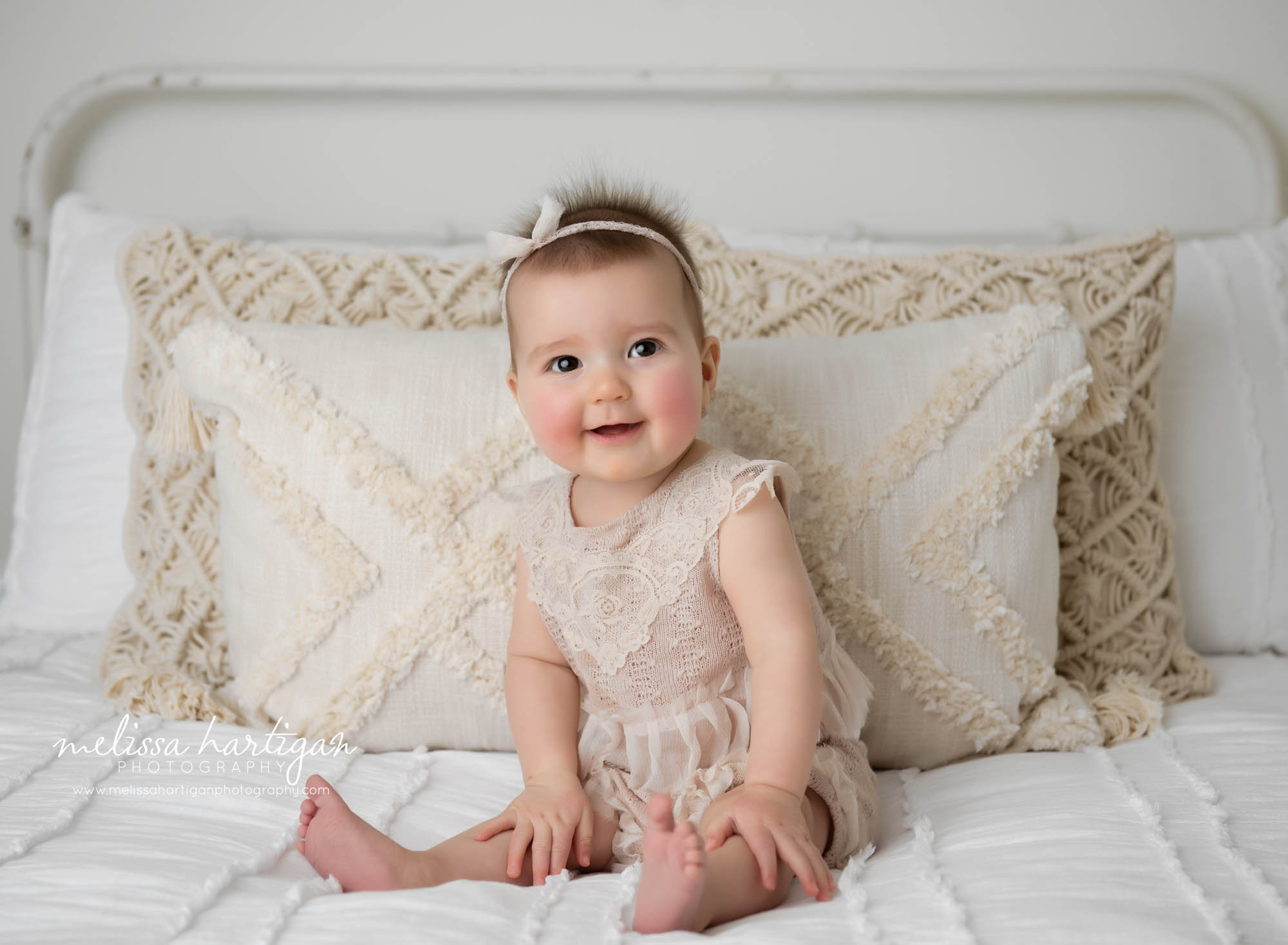 baby girl happy sitting on bed in CT photography studio