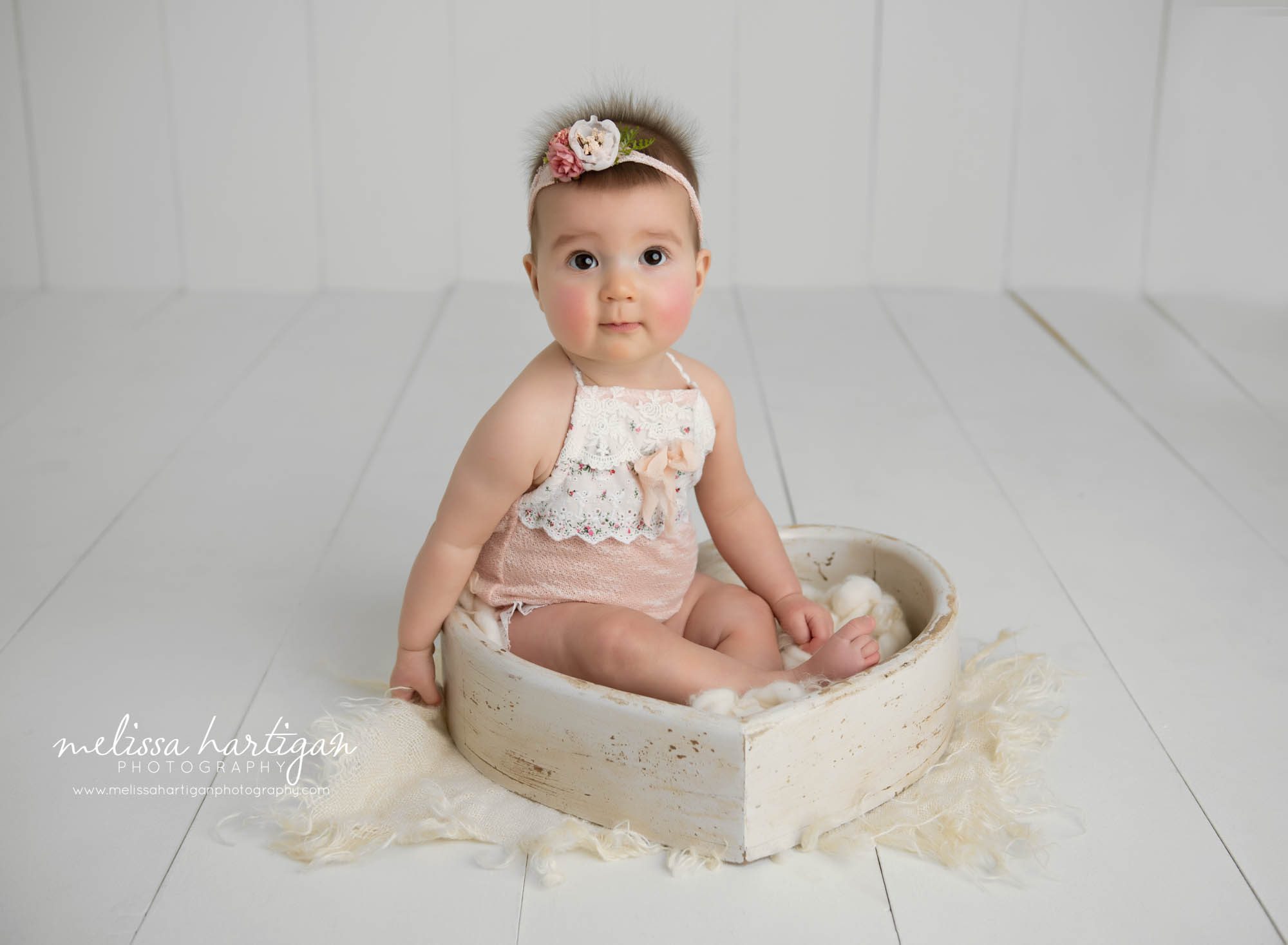 baby girl sitting in cream wooden heart prop wearing pink and cream lace outfit and flower headband Simsbury CT baby photography