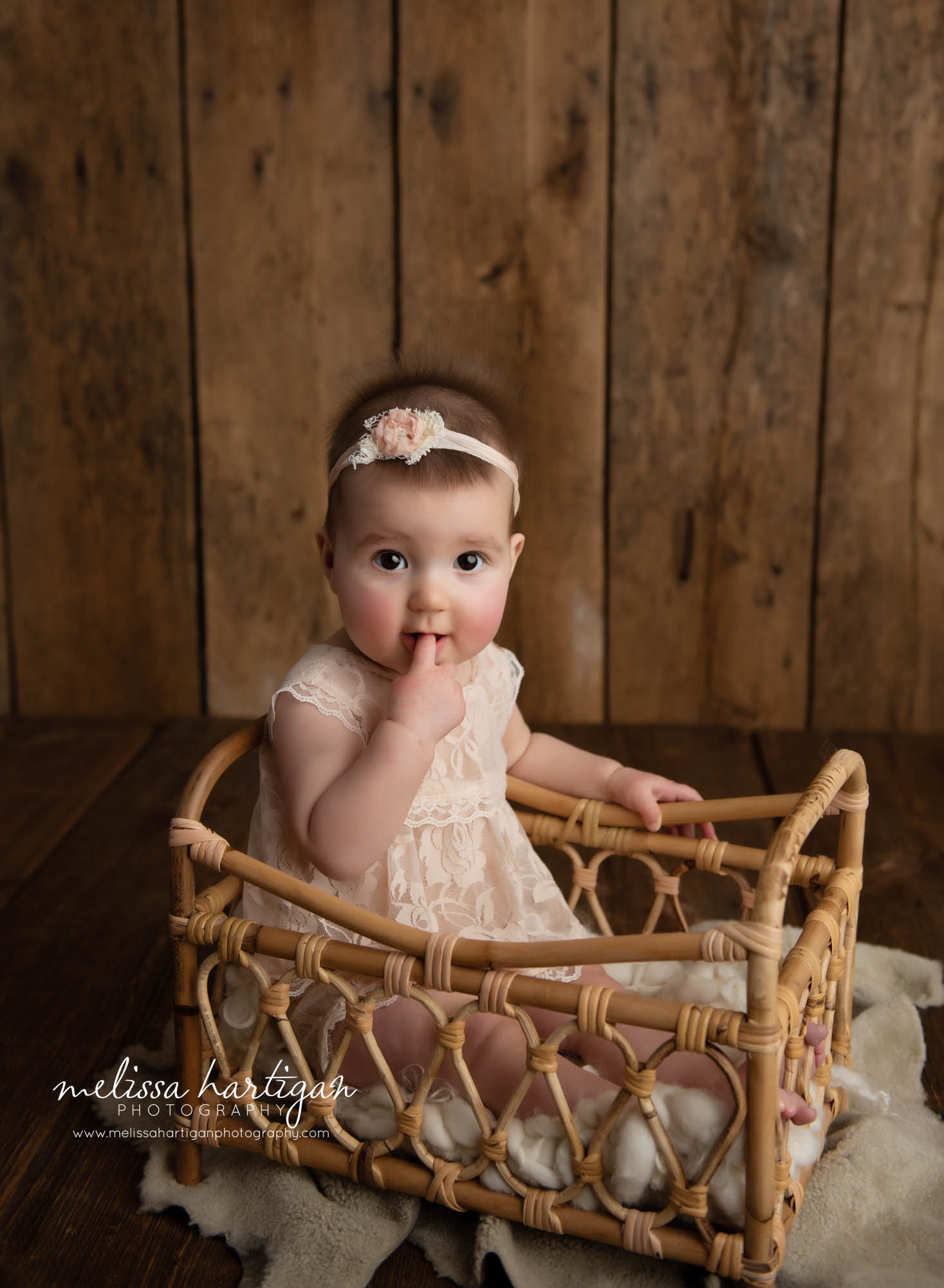 baby girl sitting in wicker basket prop in baby milestone photography session CT
