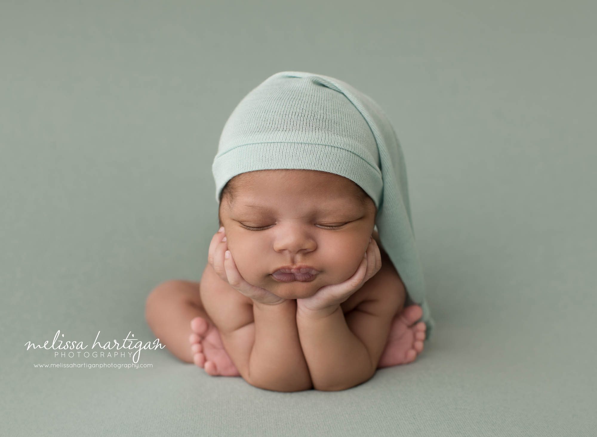 newborn baby boy posed froggy pose wearing green sleepy cap newborn photography connecticut