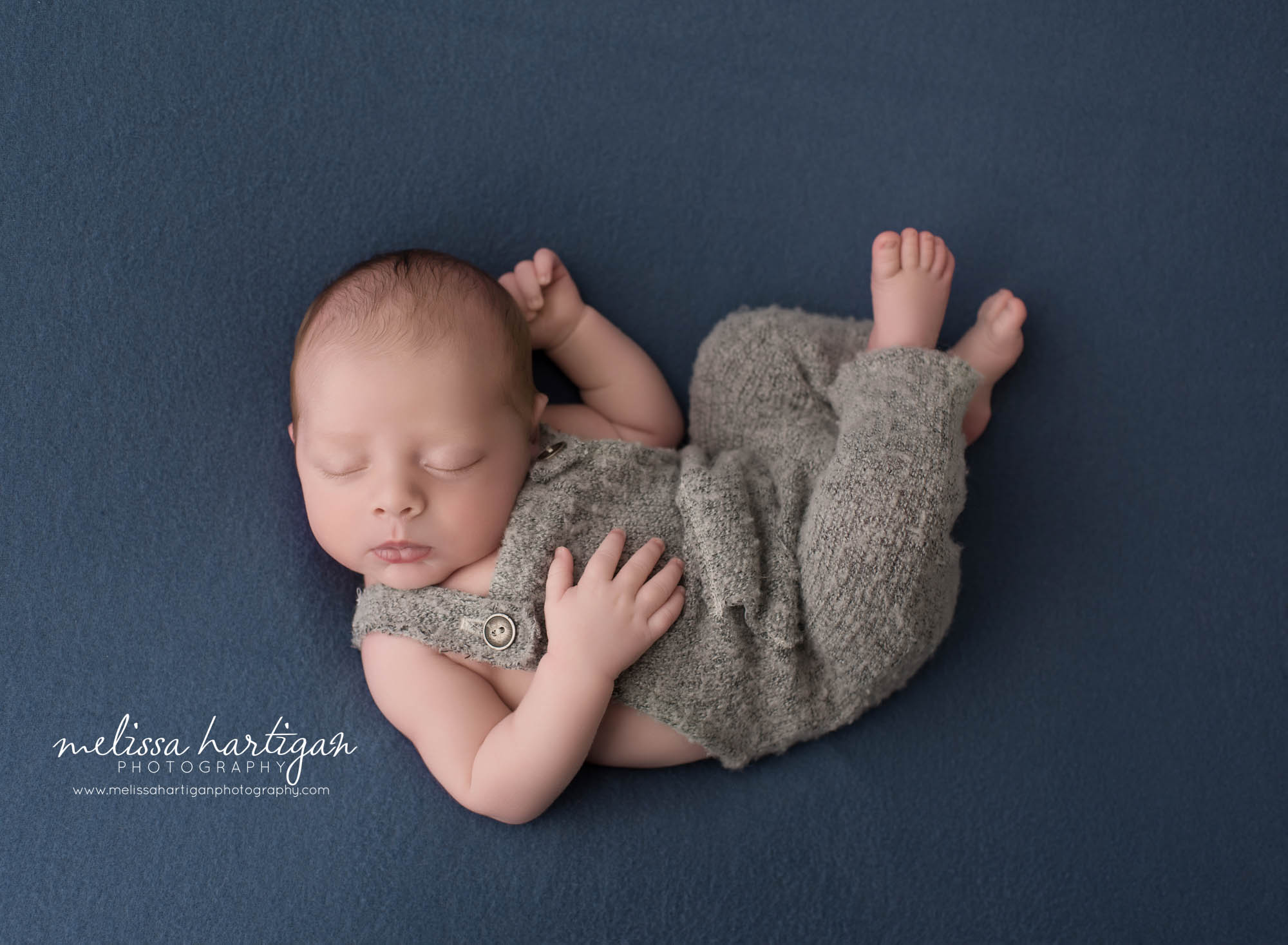 newborn baby boy wearing gray outfit posed on back sleeping