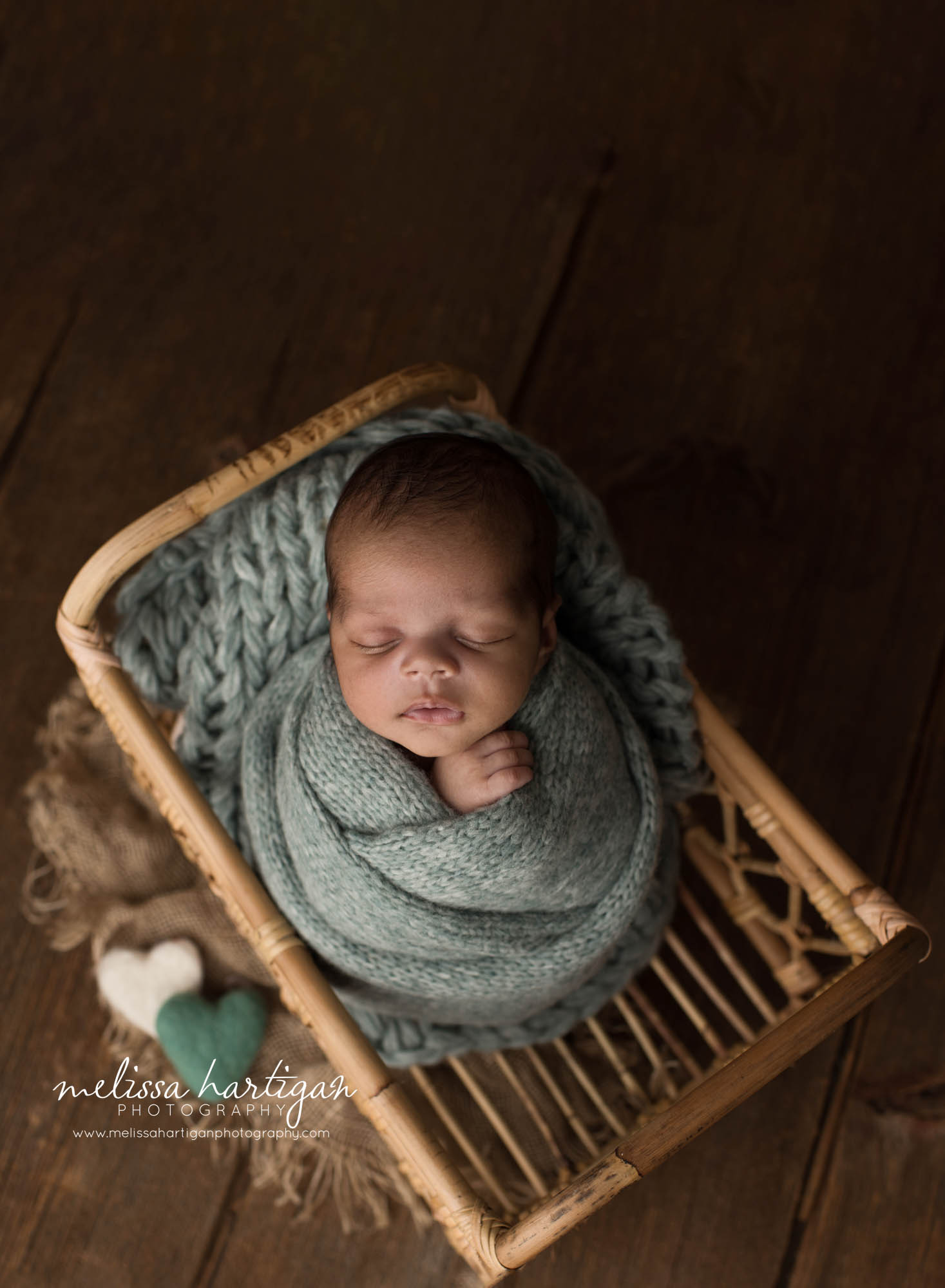 newborn baby boy wrapped in green wrap posed in basket