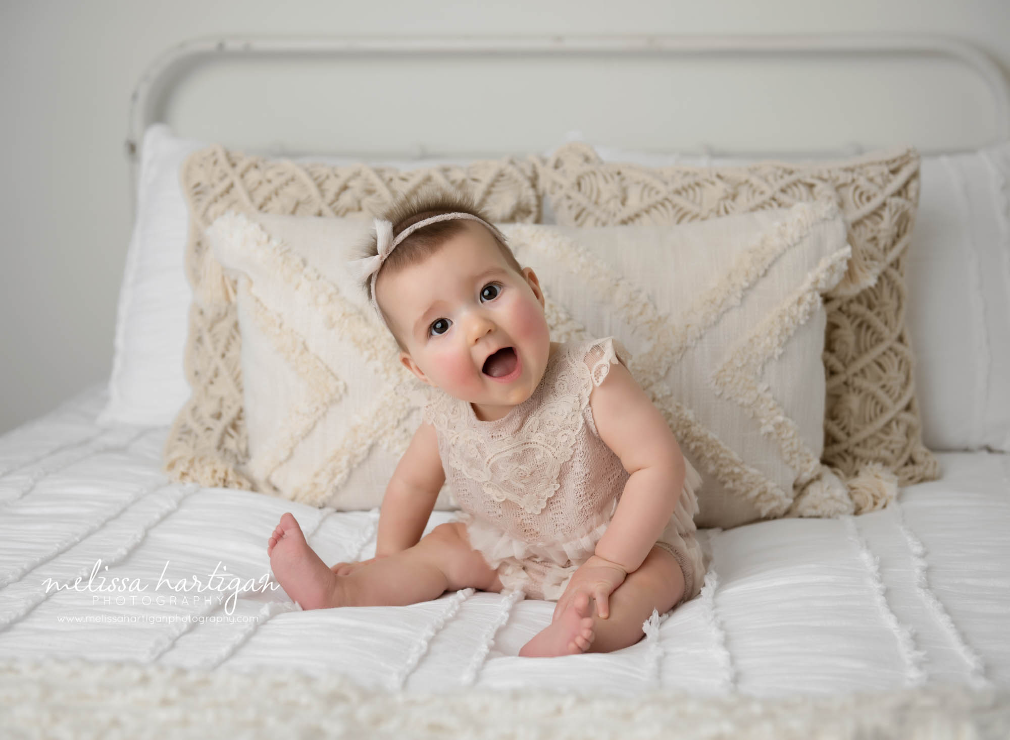 baby girl sitting up milestone photography session sitting on bed tilting head happy baby Simsbury CT baby photographer