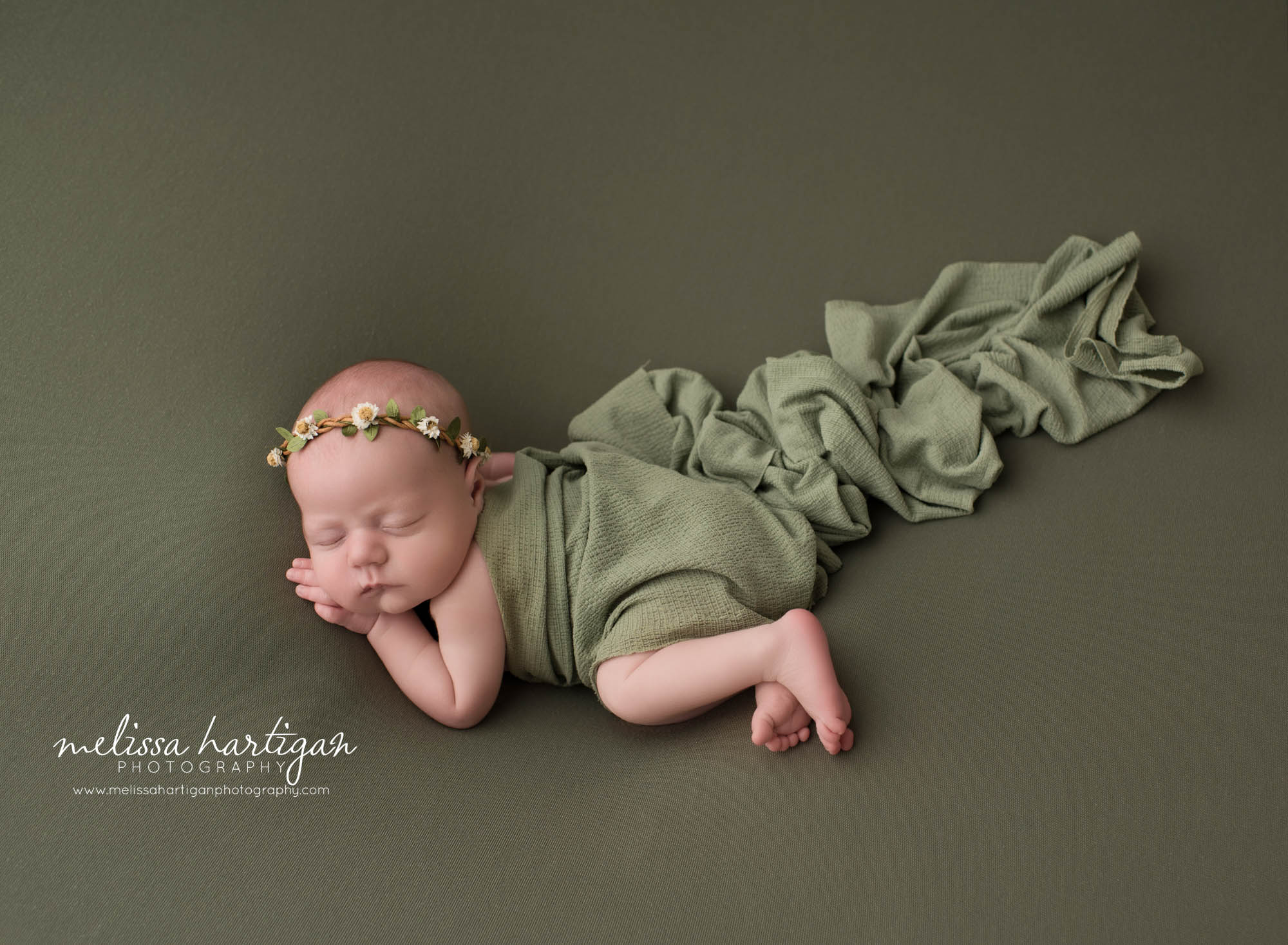 newborn baby girl posed on wide with hand under cheek wearing sage green wrap and matching headband tolland CT baby photographer