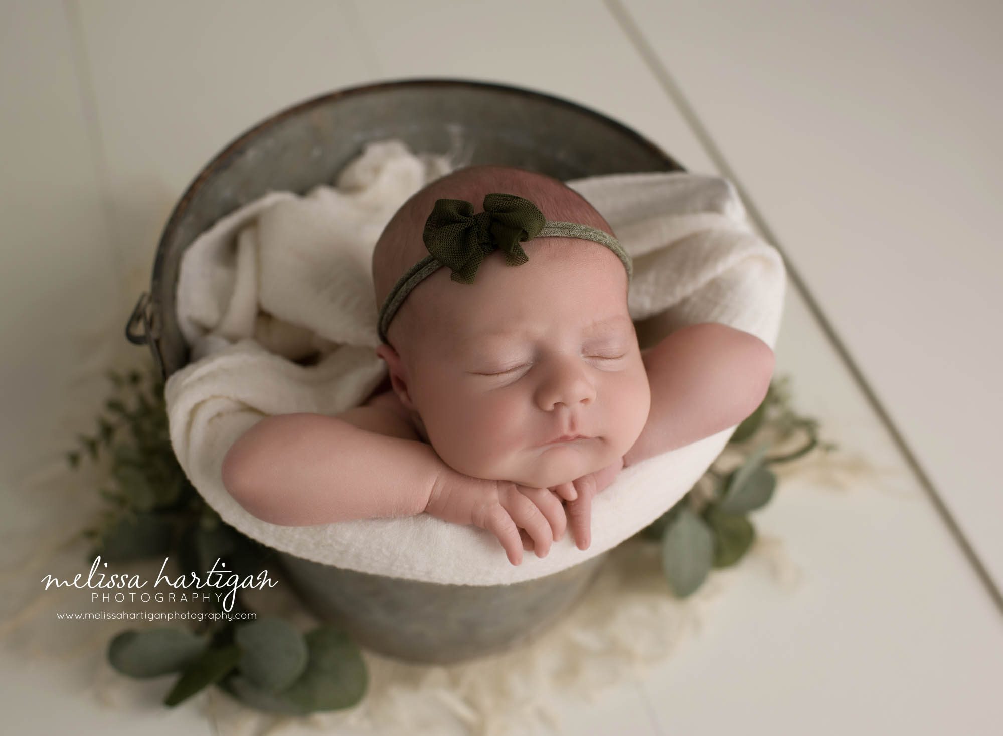 newborn baby girl posed in bucket wearing green bow headband tolland ct baby photography