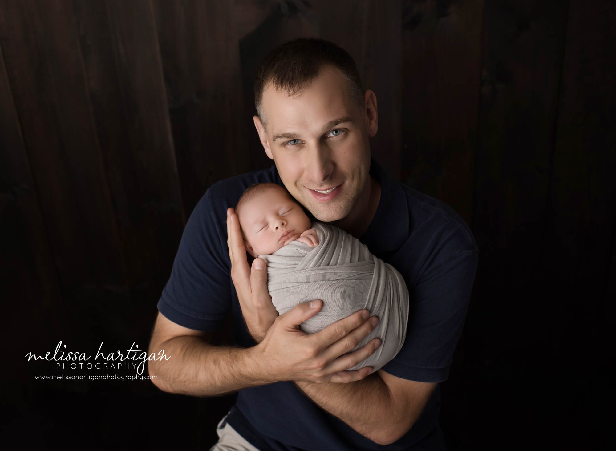 dad holding newborn son in family parent pose newborn photography CT