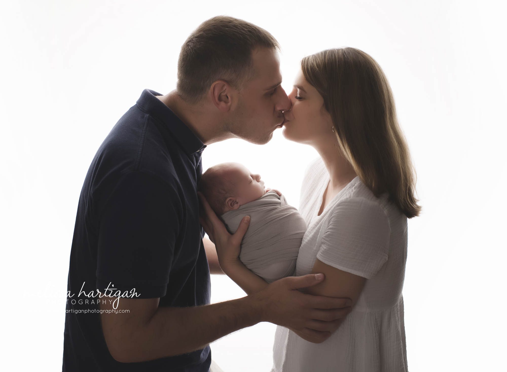 mom dad holding baby boy in studio kissing pic